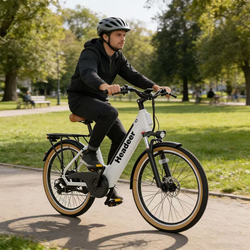 Un uomo in abiti scuri guida una e-bike bianca su un sentiero nel parco.