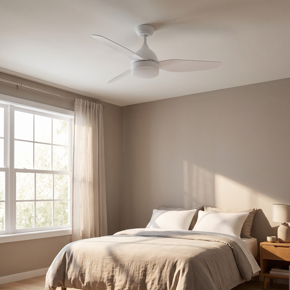 Un ventilatore a soffitto bianco è sospeso sopra un letto con biancheria da letto tortora. A sinistra c'è una finestra con tende trasparenti.