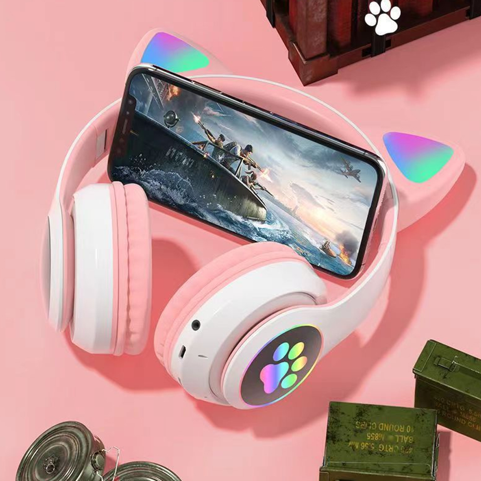 Ein pinkes Headset mit Katzenohren und leuchtender Pfote, daneben ein Handy mit Spiel.