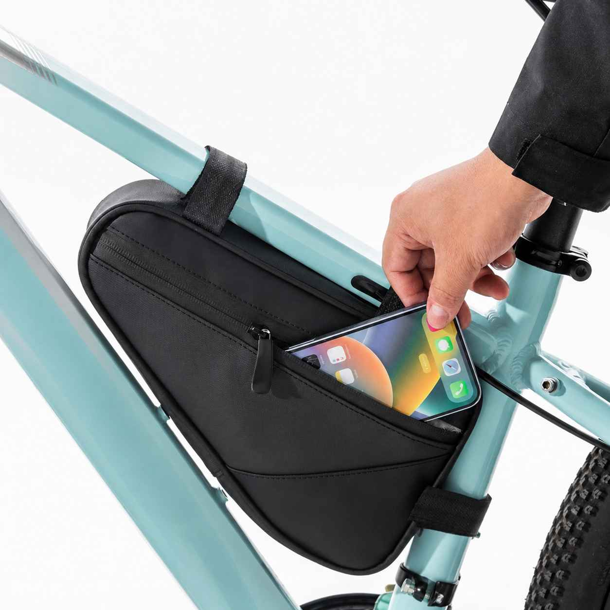 Hand legt Handy in schwarze Fahrrad Rahmentasche an blauem Fahrrad.