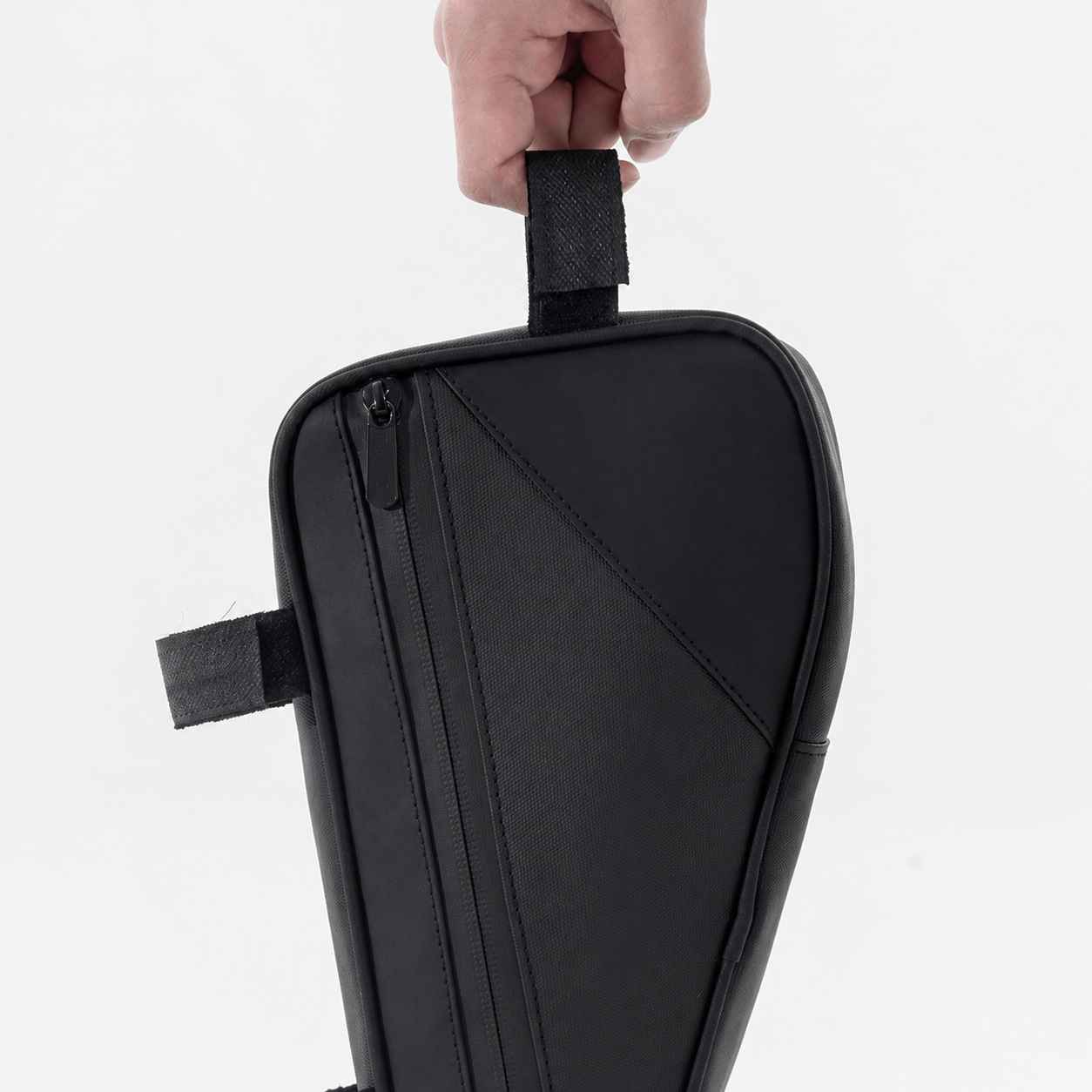 Eine Hand hält eine schwarze Fahrradtasche an einer Schlaufe.