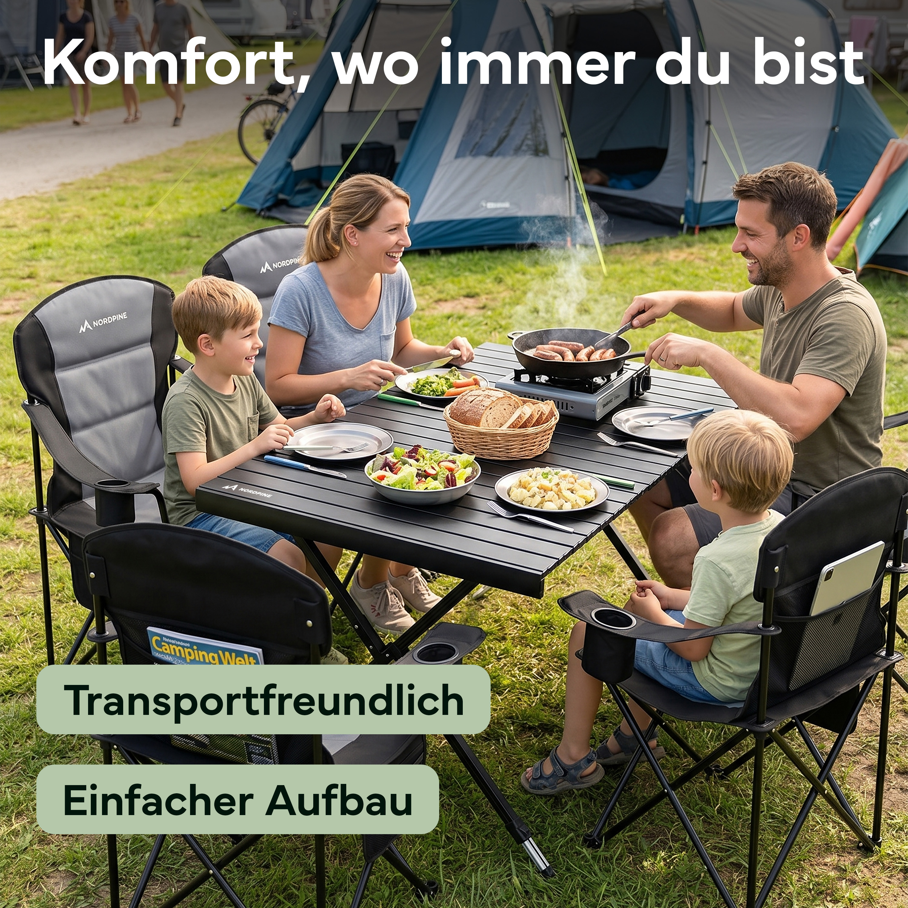 Eine Familie grillt und isst im Freien an einem Campingtisch mit Zelten im Hintergrund.