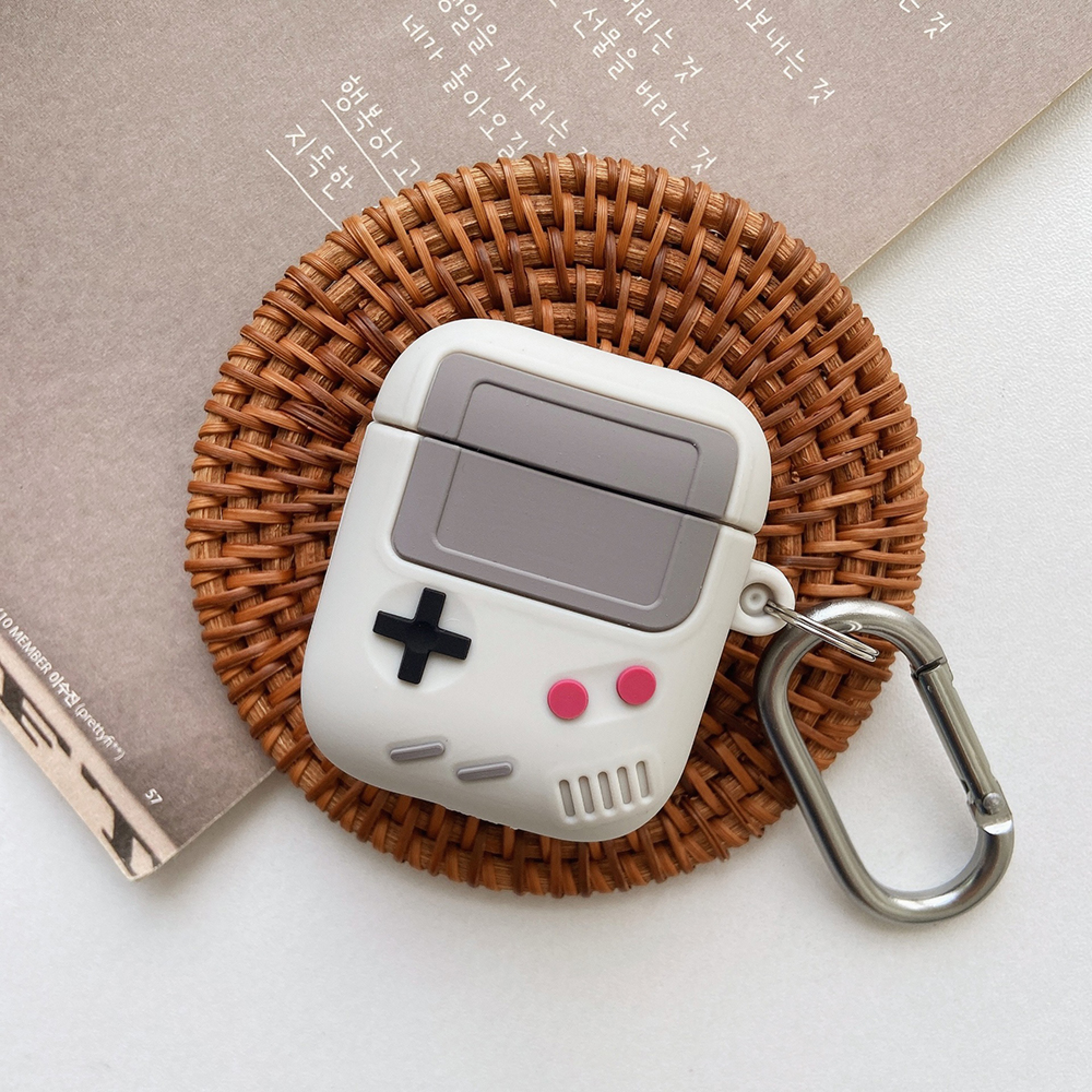 Eine weiße Hülle für Kopfhörer in Form eines Gameboys auf einem Korbteller.