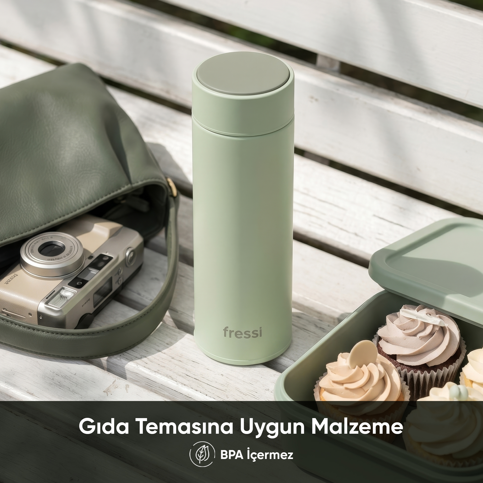 Yeşil çanta, kamera, termos ve ahşap bankta kekler.