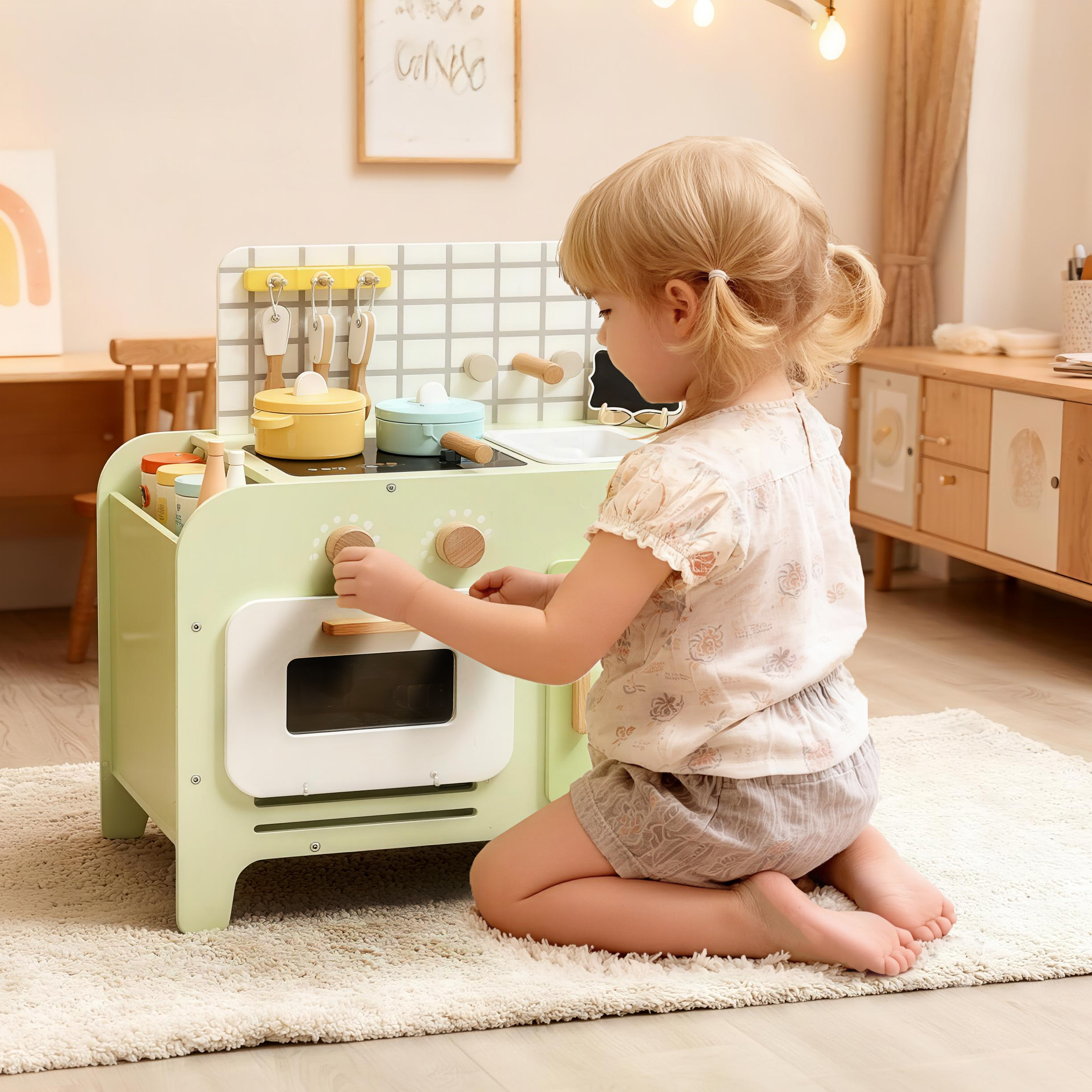 Una bambina gioca con una cucina giocattolo verde su un tappeto.