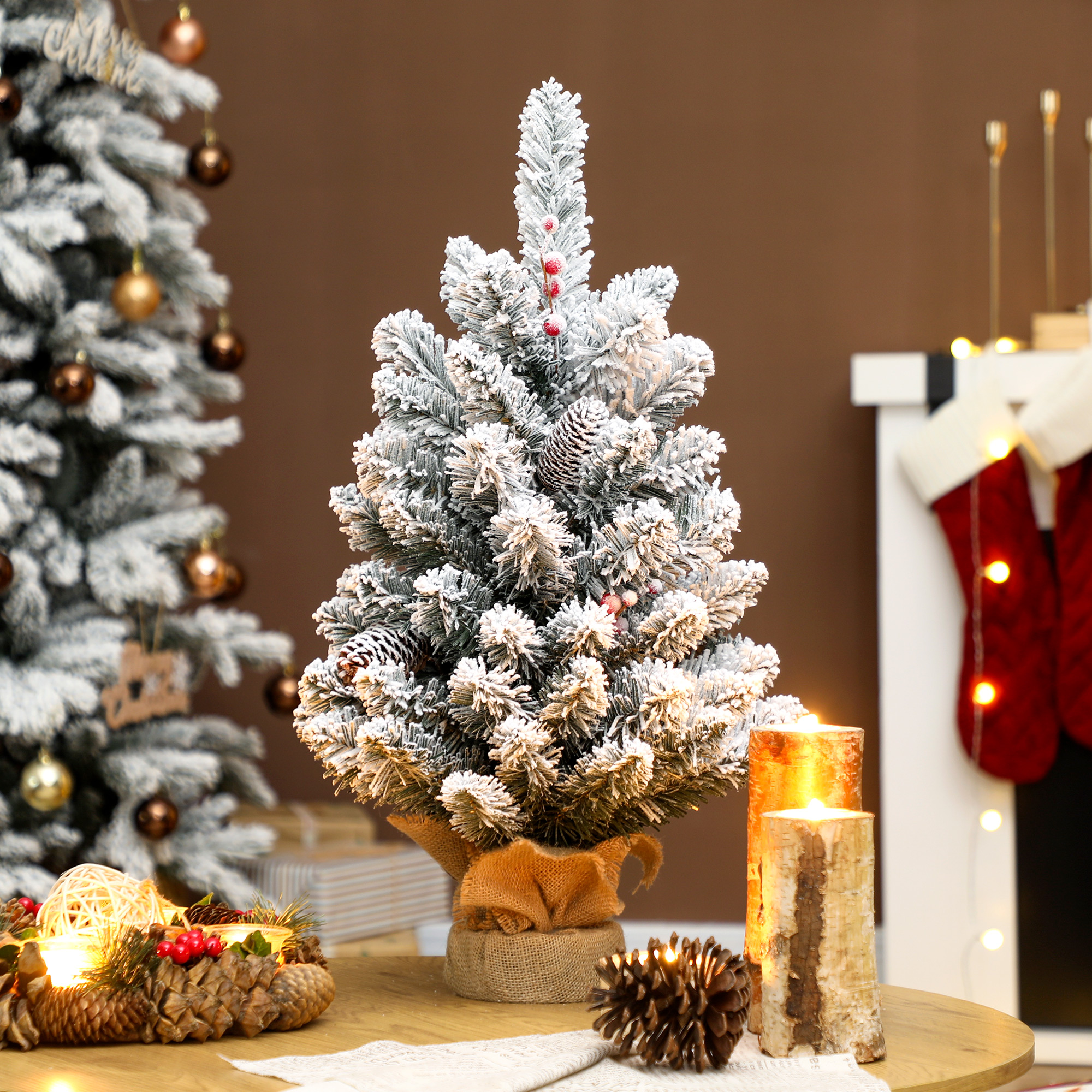 Albero di Natale innevato con pigne e bacche, candele e camino.