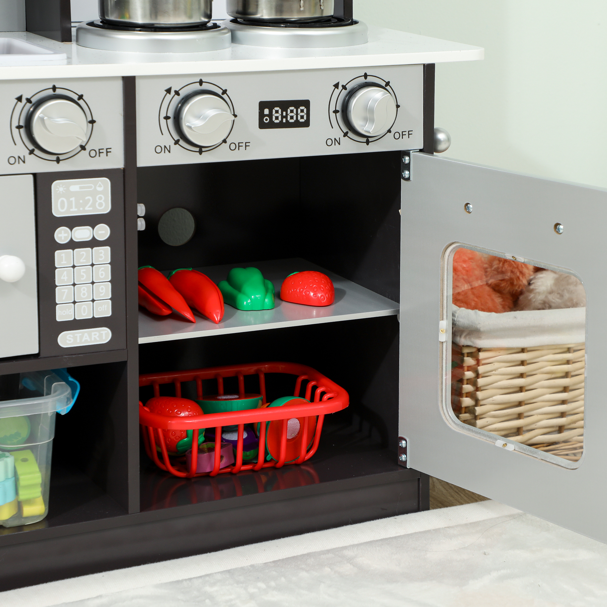 Cucina giocattolo con piano cottura, microonde, manopole e frutta/verdura giocattolo.