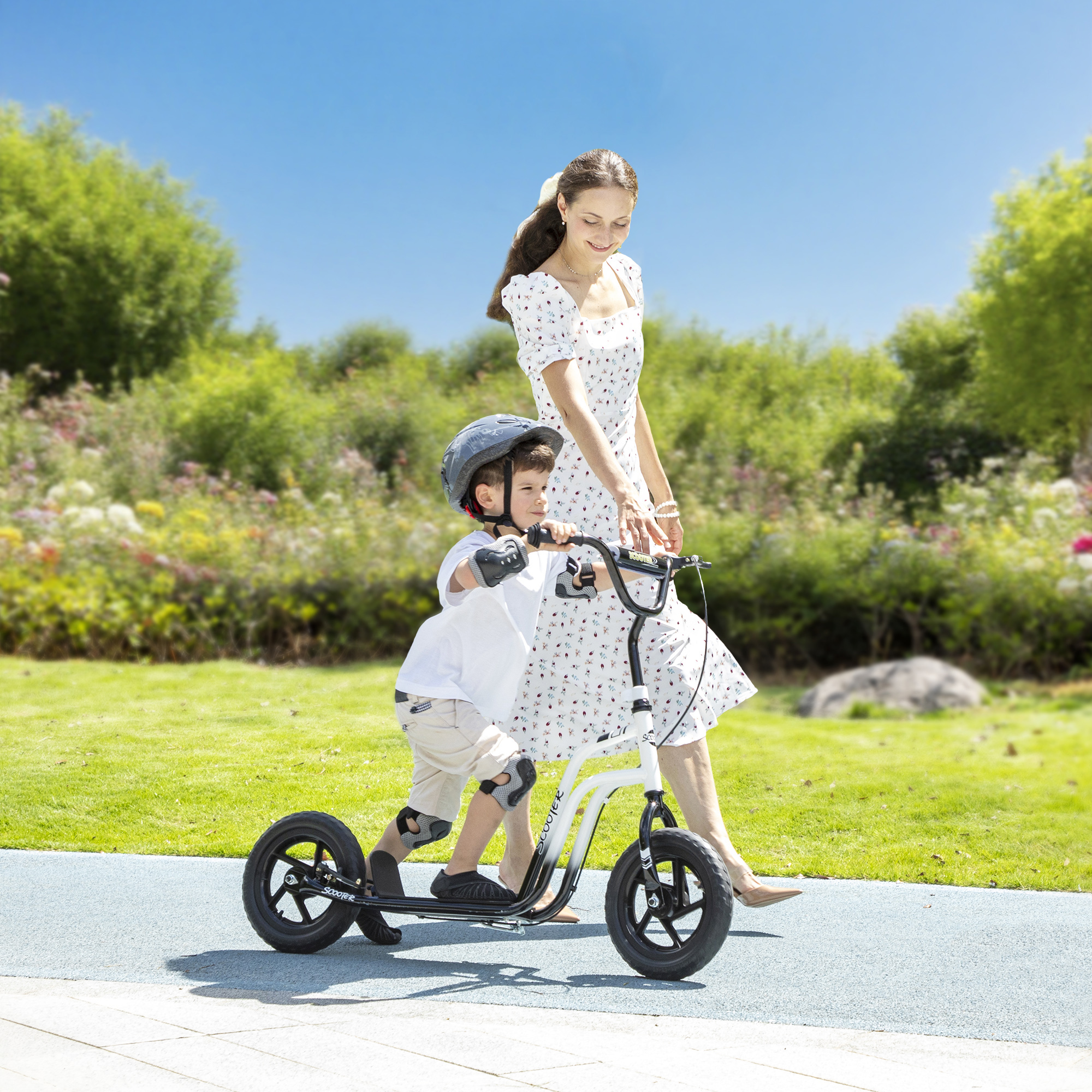 Donna accompagna bambino su monopattino in parco in una giornata di sole.