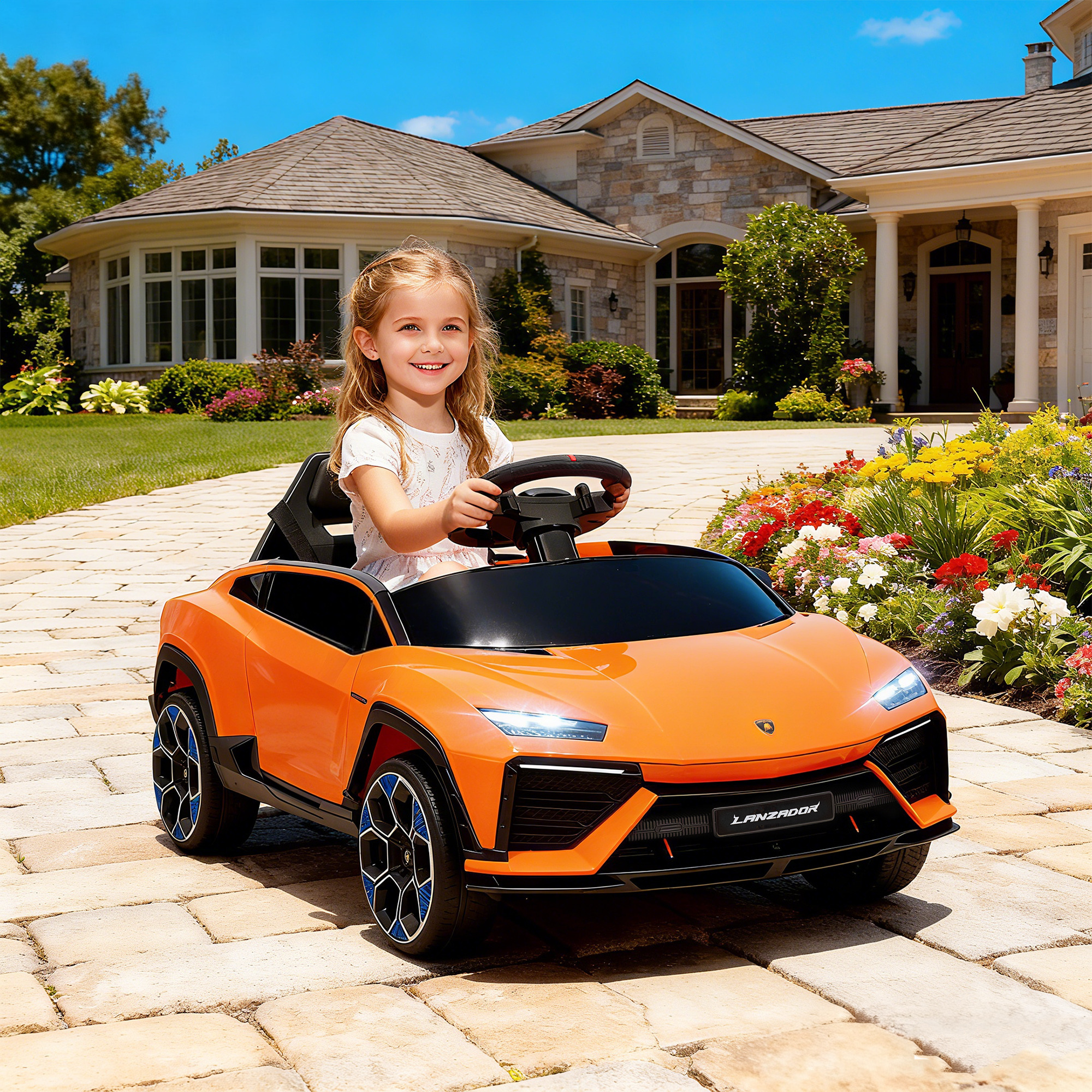 Una bambina sorride seduta in un'auto giocattolo arancione davanti a una casa.
