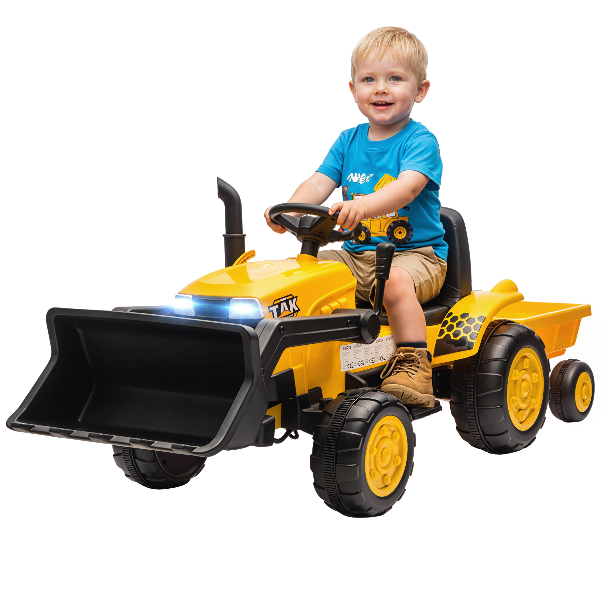 Un bambino guida un trattore giocattolo giallo con pala e rimorchio.