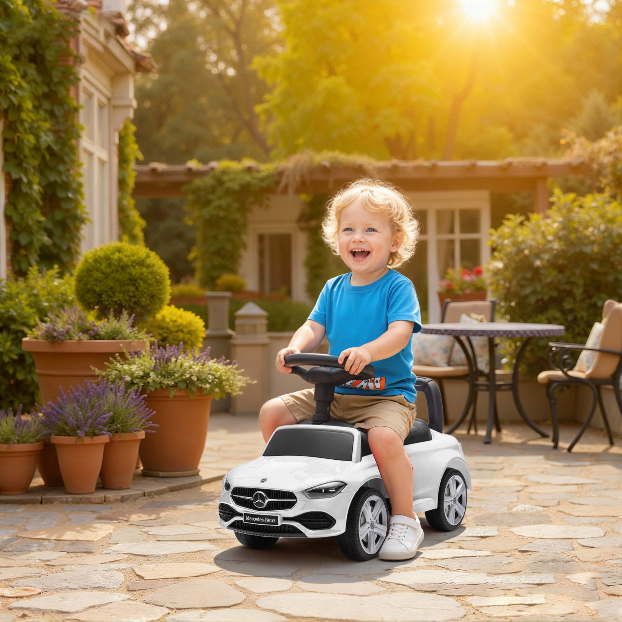 Un bambino biondo guida un'auto giocattolo bianca in un giardino soleggiato.