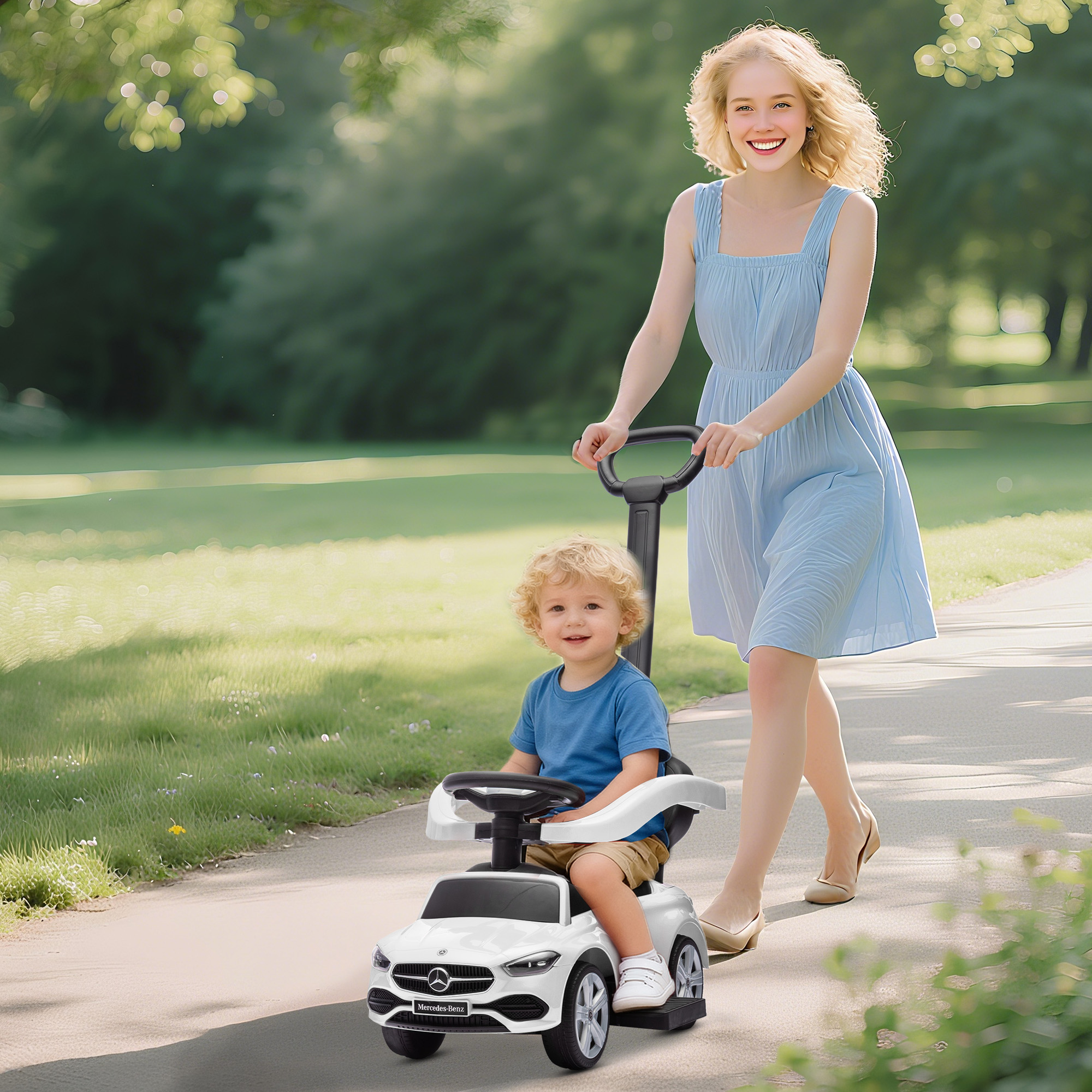 Una donna spinge un'auto giocattolo bianca con un bambino su un sentiero del parco.