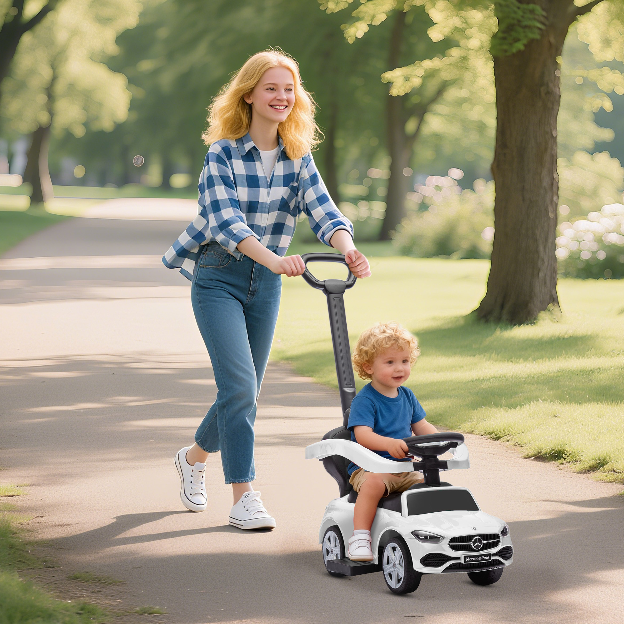 Una donna spinge un'auto giocattolo bianca con un bambino su un sentiero del parco.