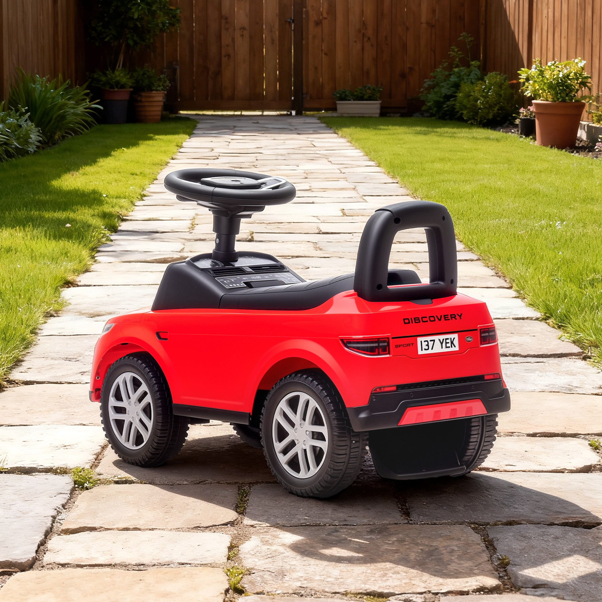 Una macchinina rossa con volante nero su un sentiero di pietra in un giardino.