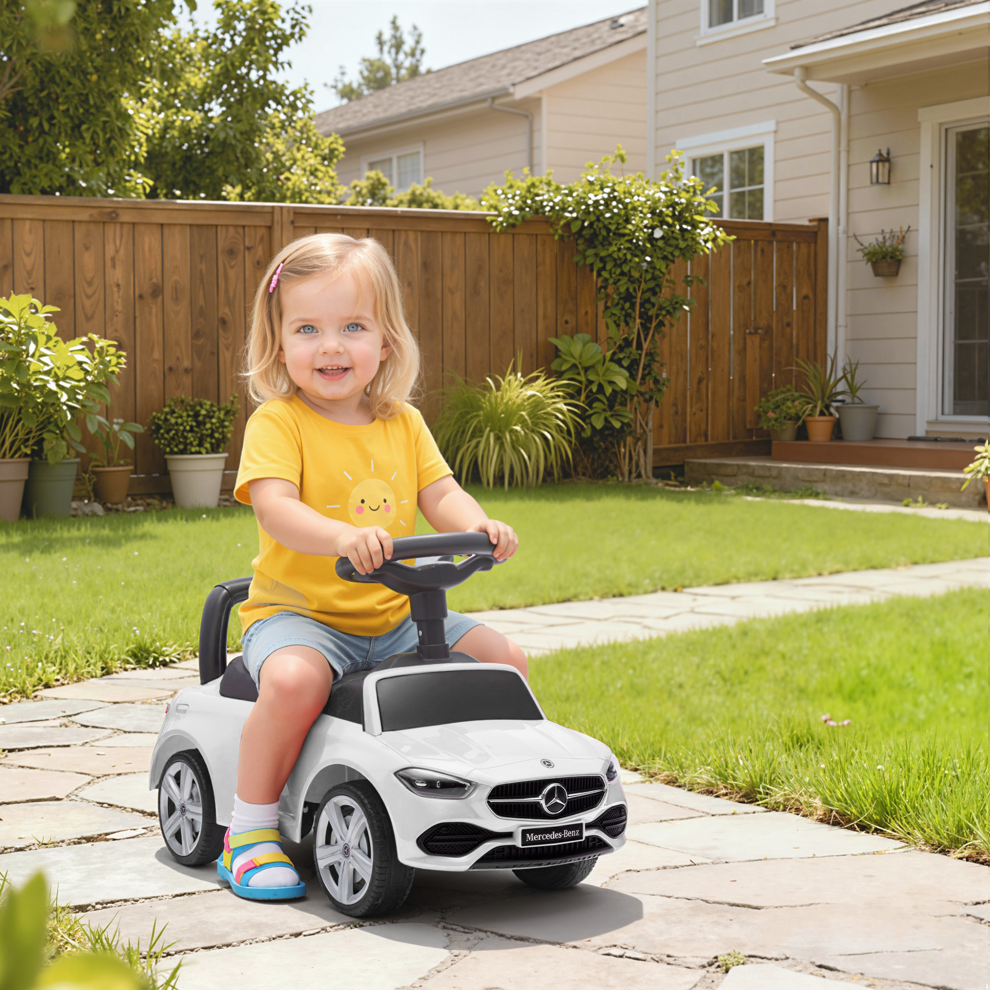 Una bambina è seduta su un'auto giocattolo bianca in un cortile.