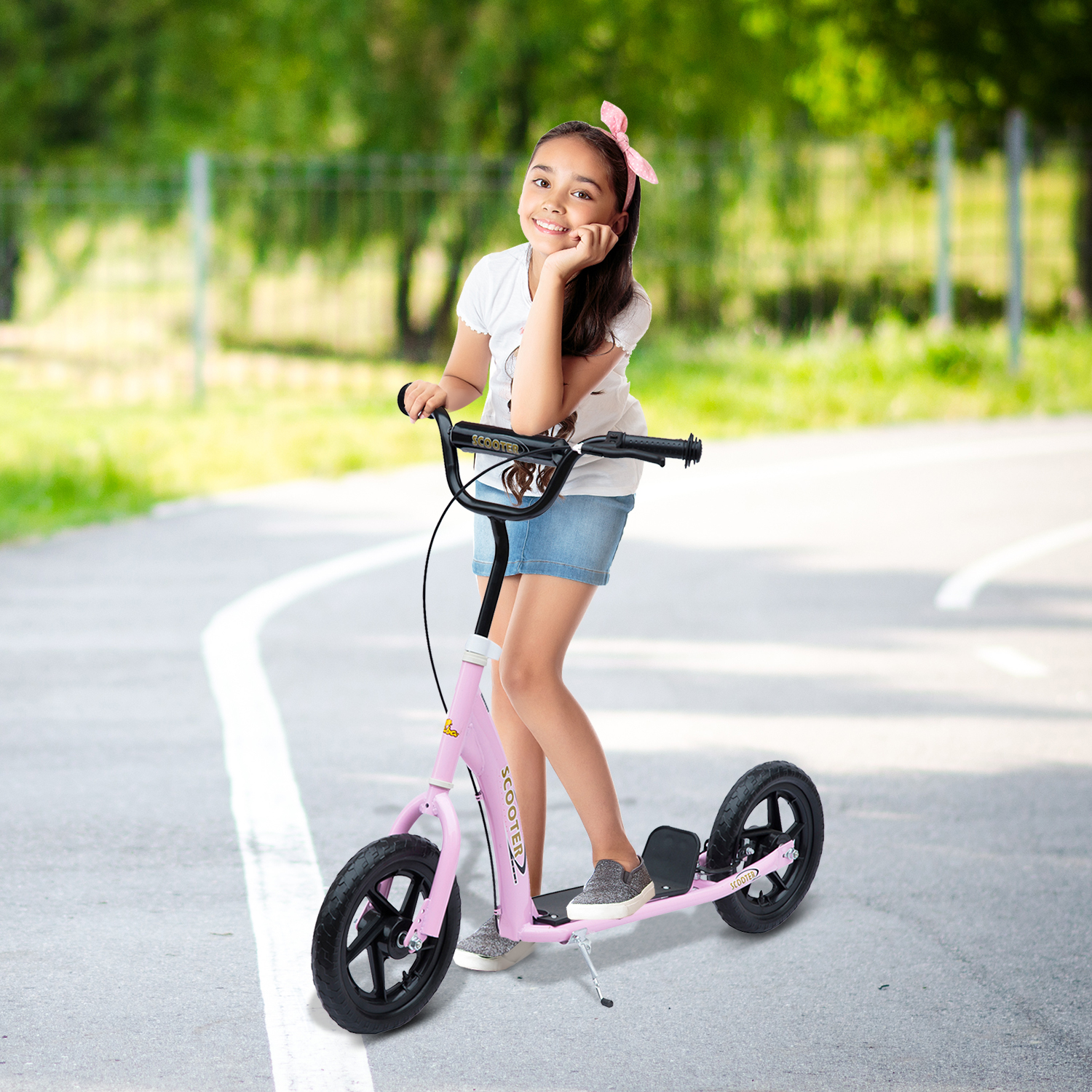Una bambina con camicia bianca e gonna di jeans sorride, appoggiando il mento sulla mano, su un monopattino rosa.