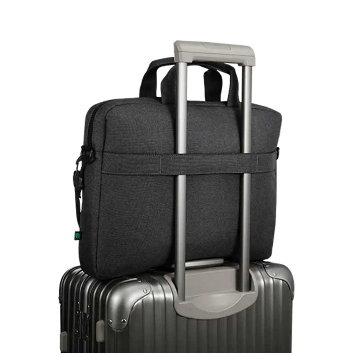 Una borsa porta computer scura sopra una valigia argentata con manico estensibile.