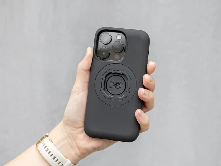 Eine Hand hält ein schwarzes iPhone mit einer Quad Lock Hülle.