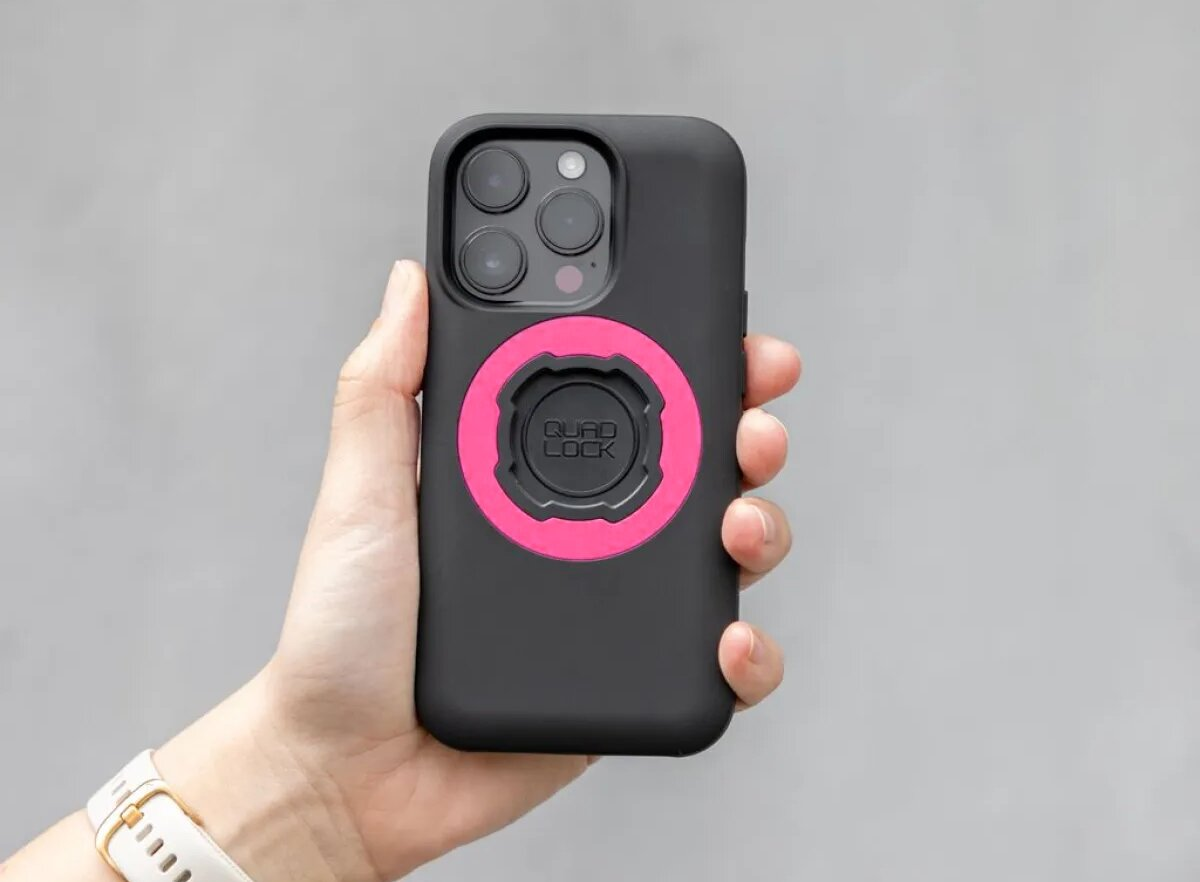 Eine Hand hält ein schwarzes iPhone mit einer pinken Quad Lock Halterung.