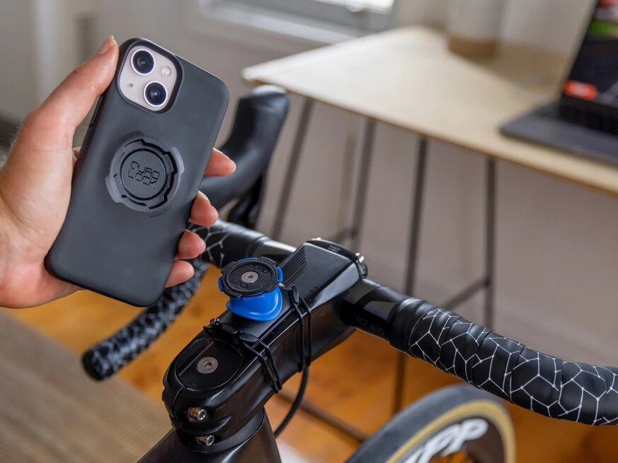 Person hält schwarzes Handy über Fahrradlenker mit Halterung.
