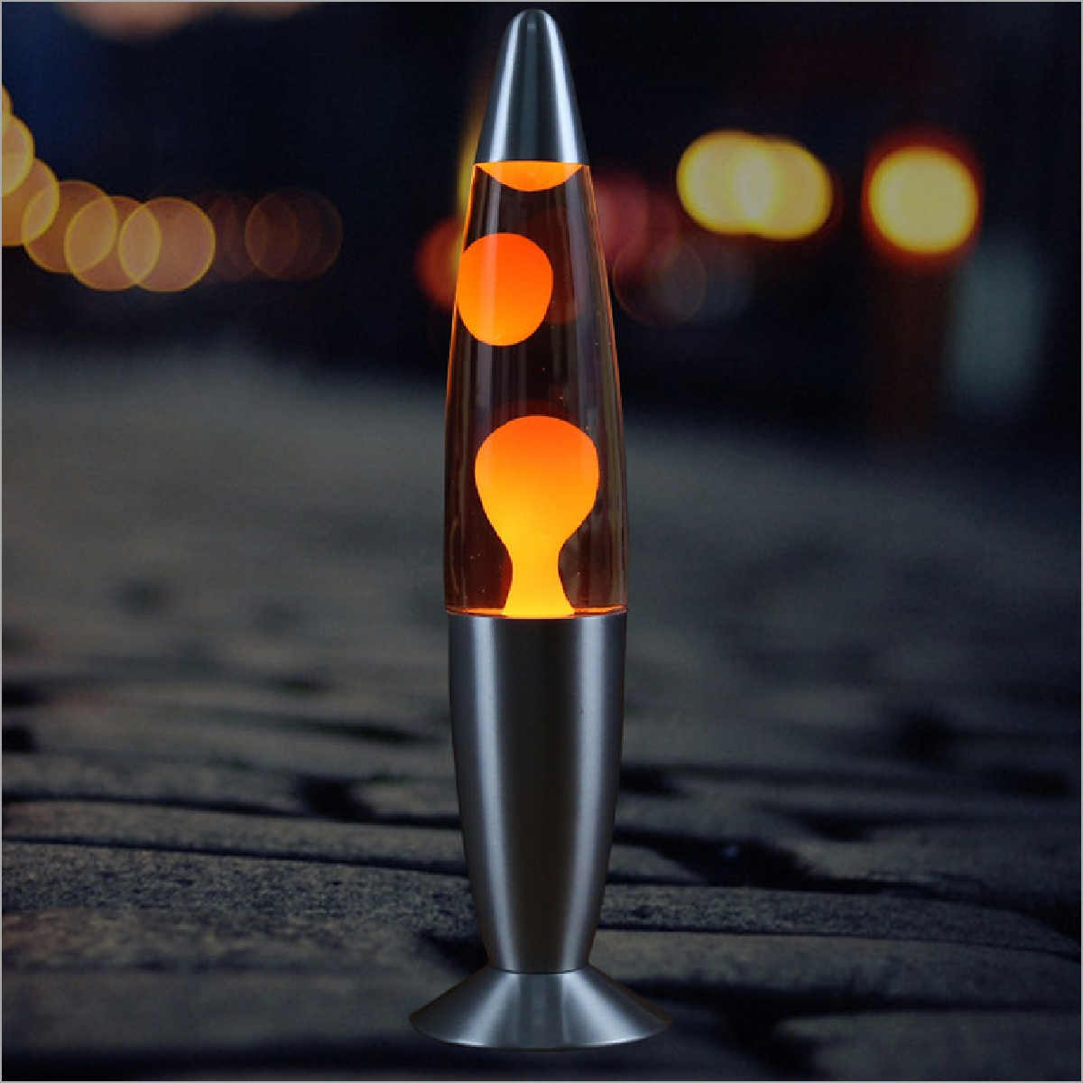 Eine orangefarbene Lavalampe leuchtet auf einem dunklen Untergrund.