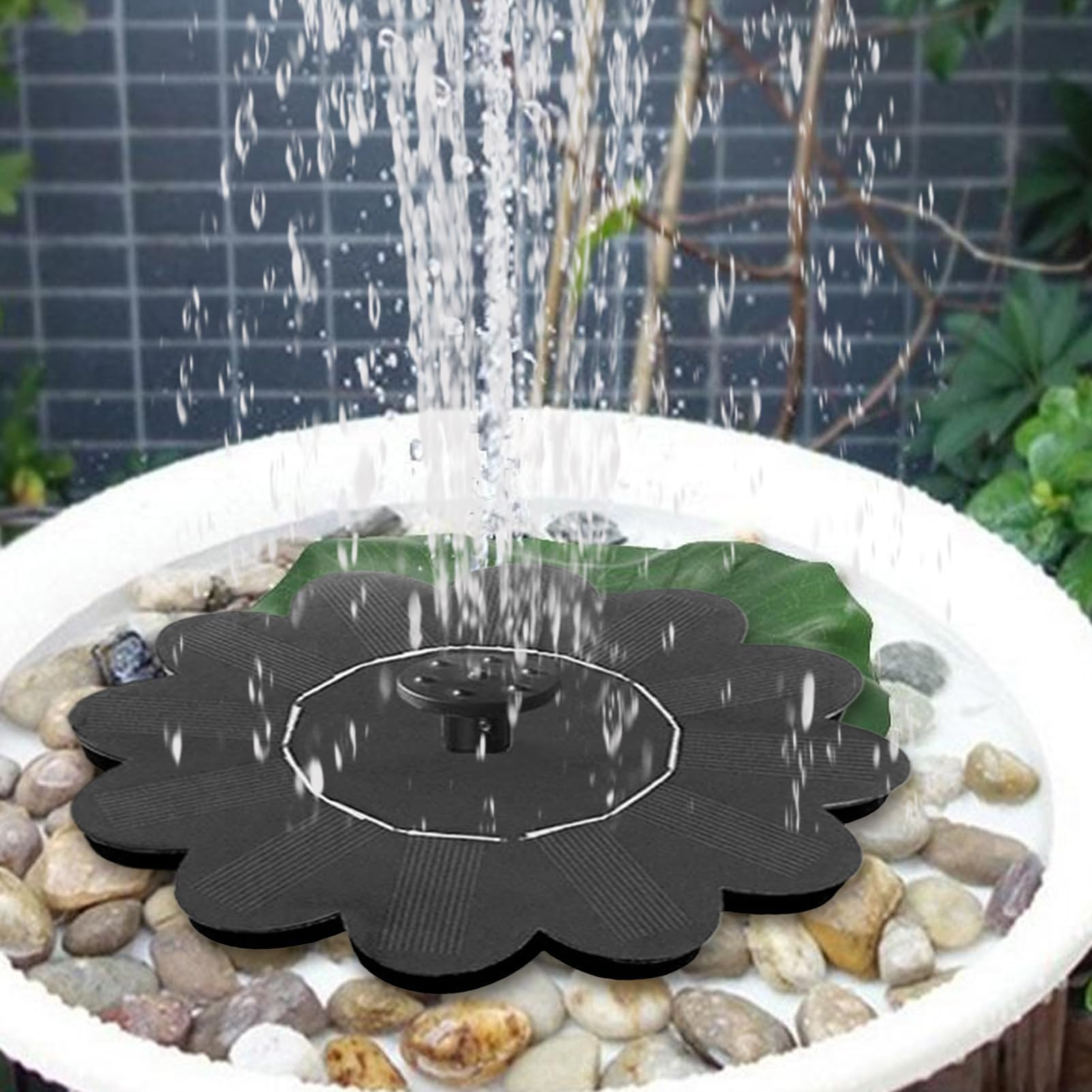 Eine Solarfontäne in Blumenform mit Wasserstrahl auf Kieselsteinen.