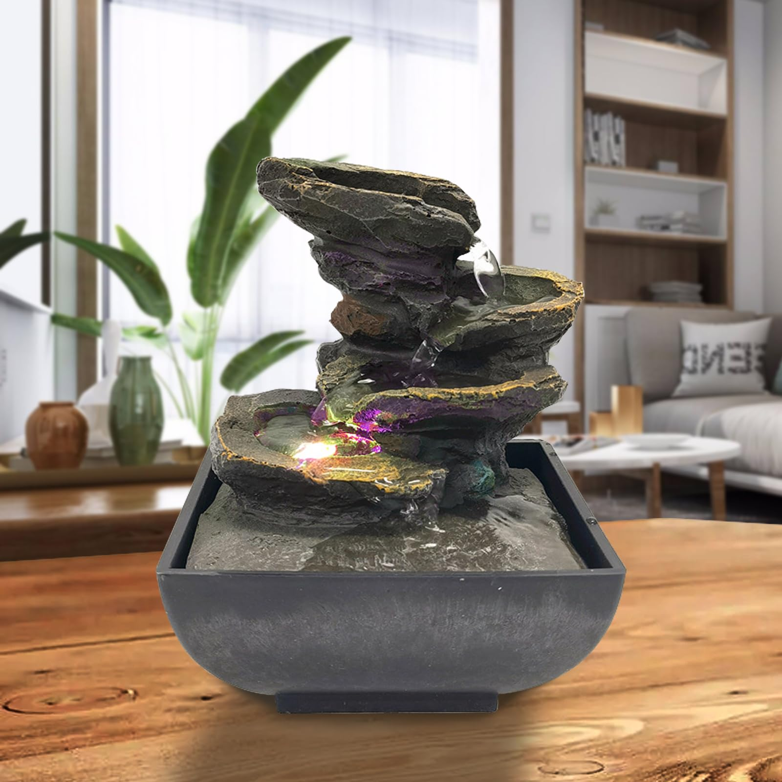 Ein Mini-Brunnen aus Stein mit Lichtern auf einem Holztisch.