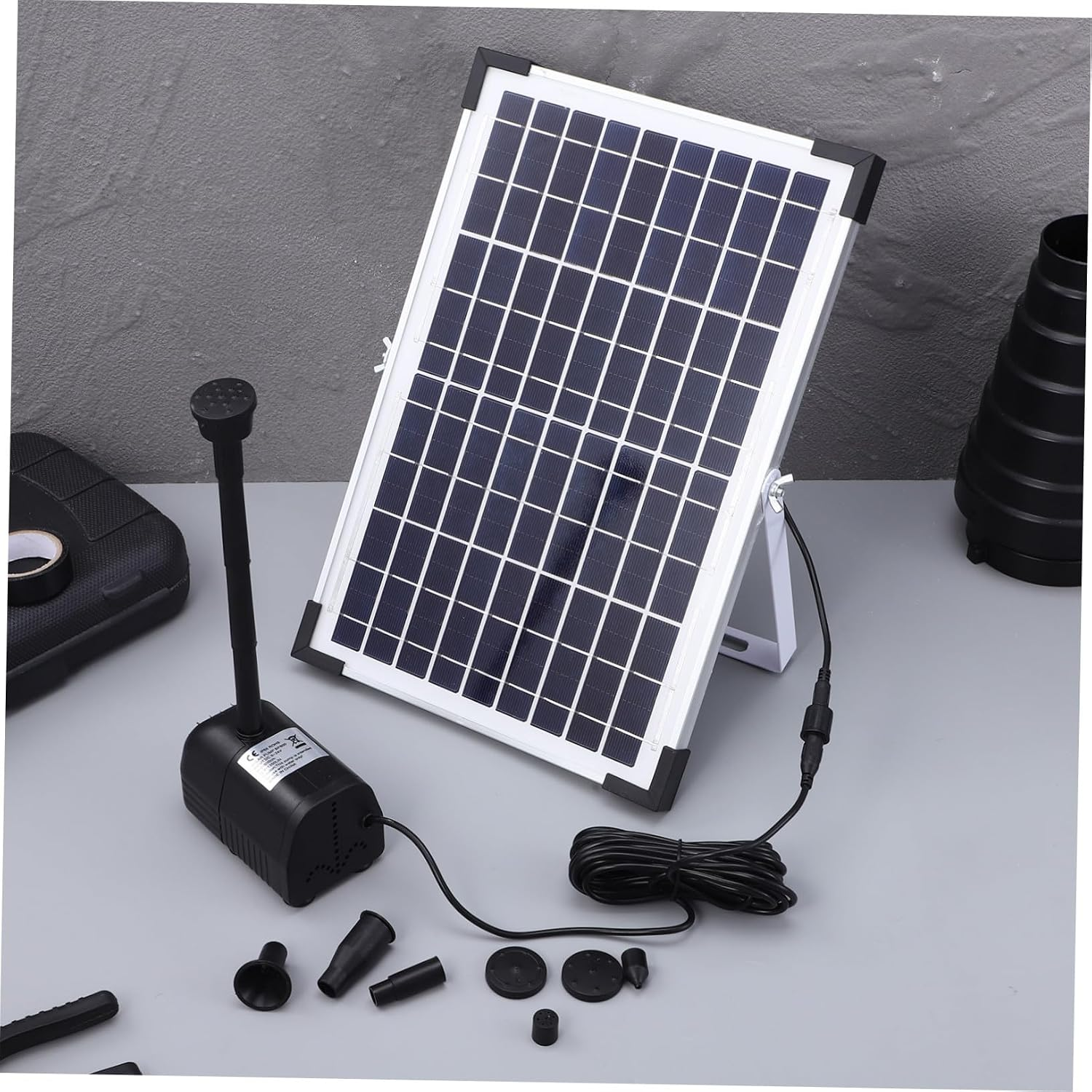 Solarpanel mit Wasserpumpe und Zubehör auf grauem Hintergrund.