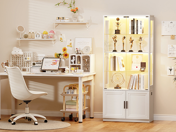 Ein weißer Schreibtisch mit einem Laptop und einem Stuhl. Rechts steht ein beleuchteter Schrank mit Trophäen.