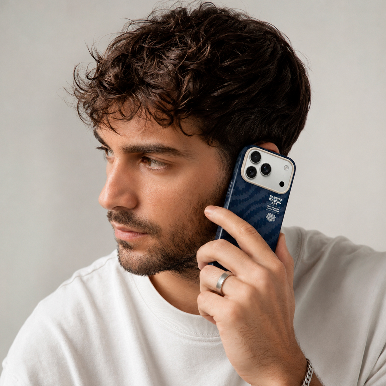 Hombre con pelo rizado al teléfono con funda azul oscuro.