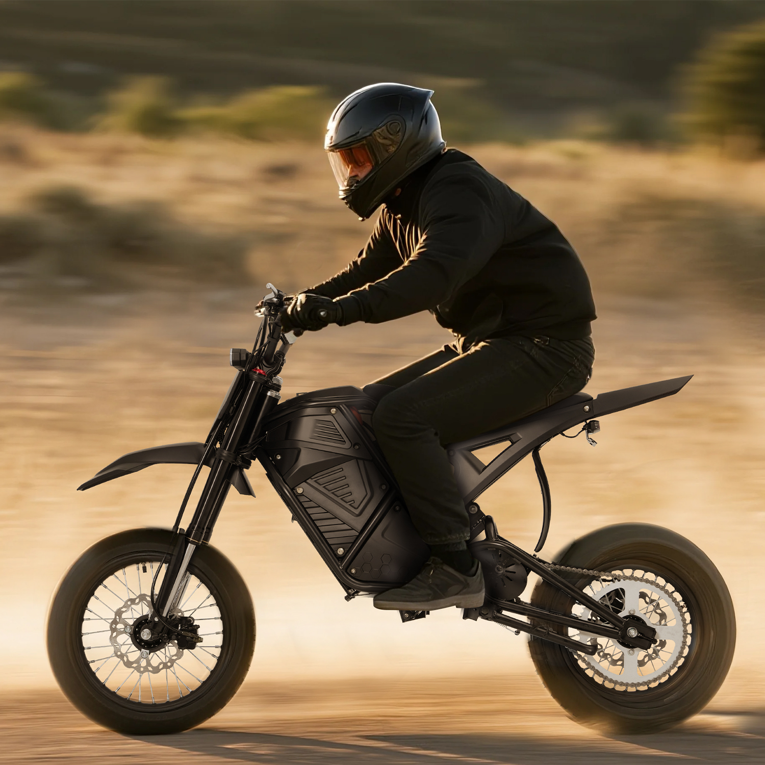 Ein Mann in schwarzer Kleidung fährt ein schwarzes Motorrad in einer Wüstenlandschaft.