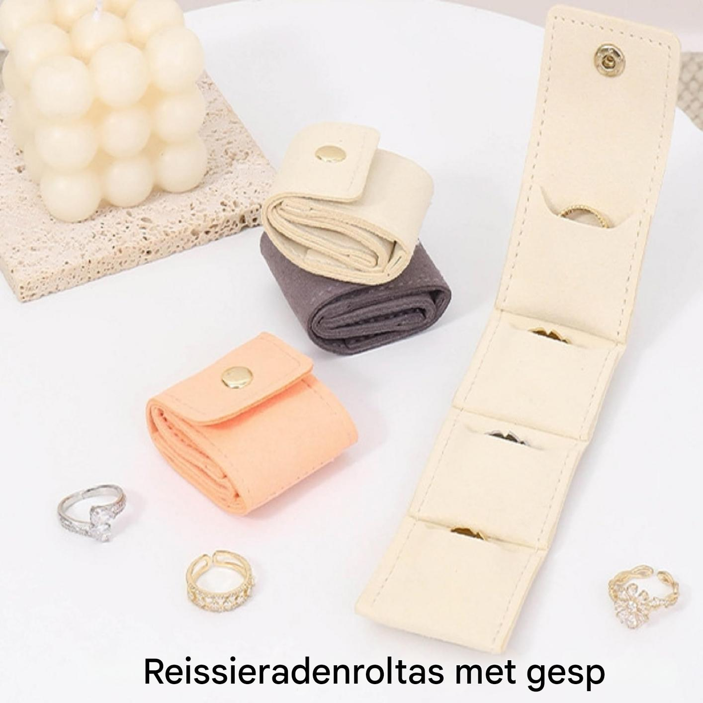Ein aufklappbares cremefarbenes Schmucketui mit drei Fächern und Ringen.