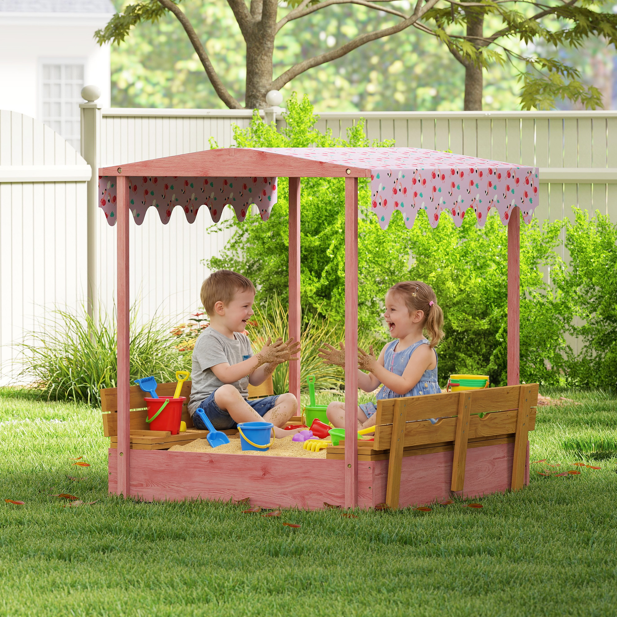 Due bambini giocano in una sandbox rosa con tetto a baldacchino di fenicotteri.
