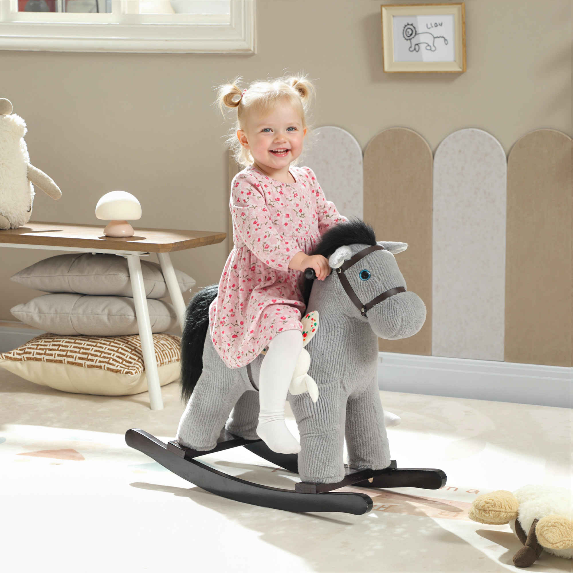 Una bambina felice cavalca un cavallo a dondolo grigio in una stanza per bambini.