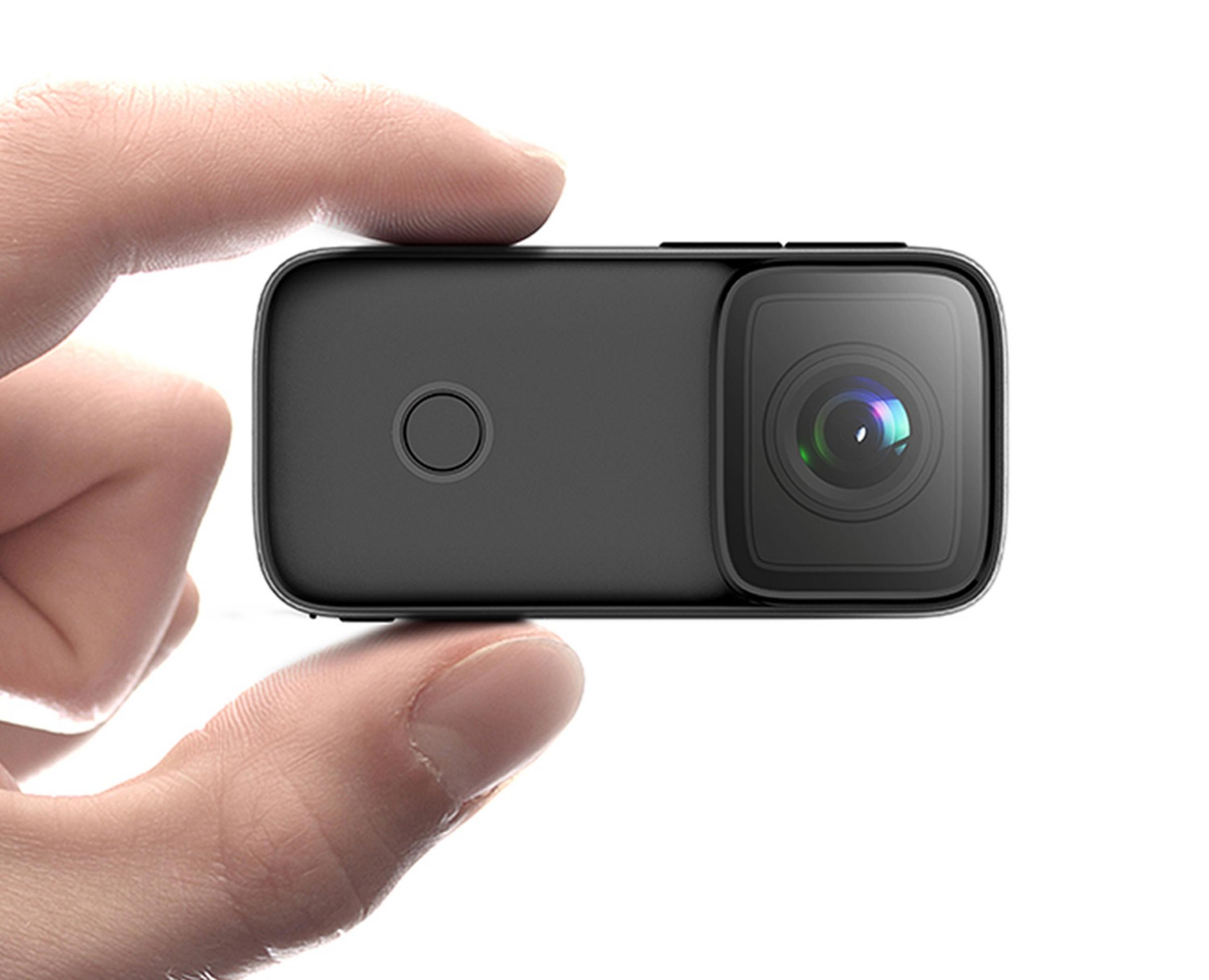 Una persona tiene una piccola fotocamera nera con obiettivo e pulsante circolare.