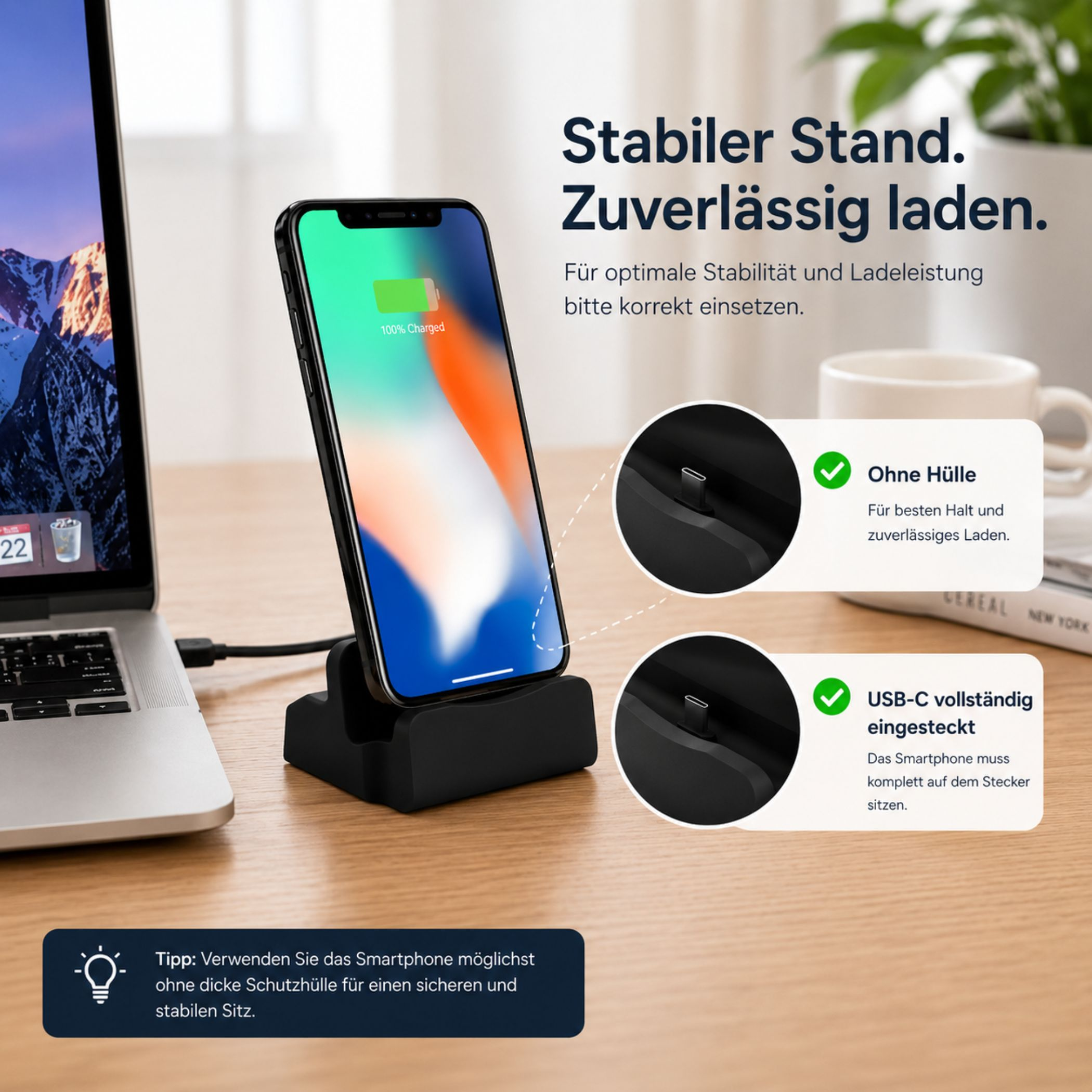Smartphone lädt auf schwarzem Ständer neben Laptop. Hinweise zu Hülle und USB-C.