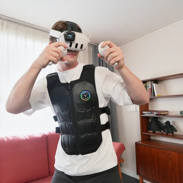 Hombre con casco de RV y chaleco háptico juega con mandos.