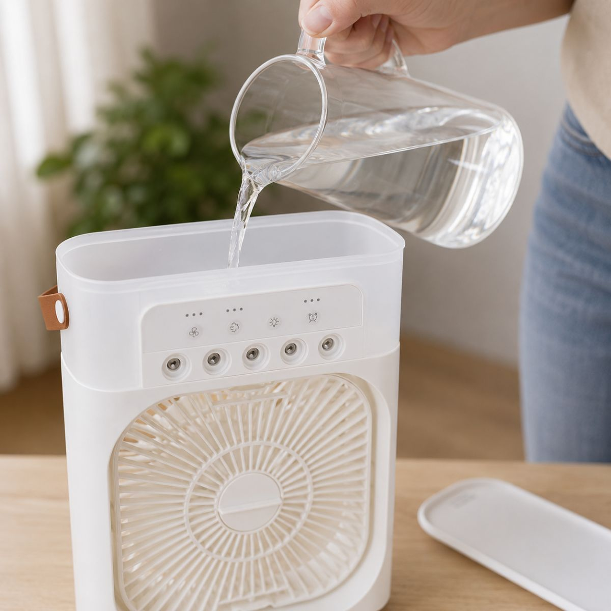 Water is poured from a glass into a white fan sitting on a wooden table.