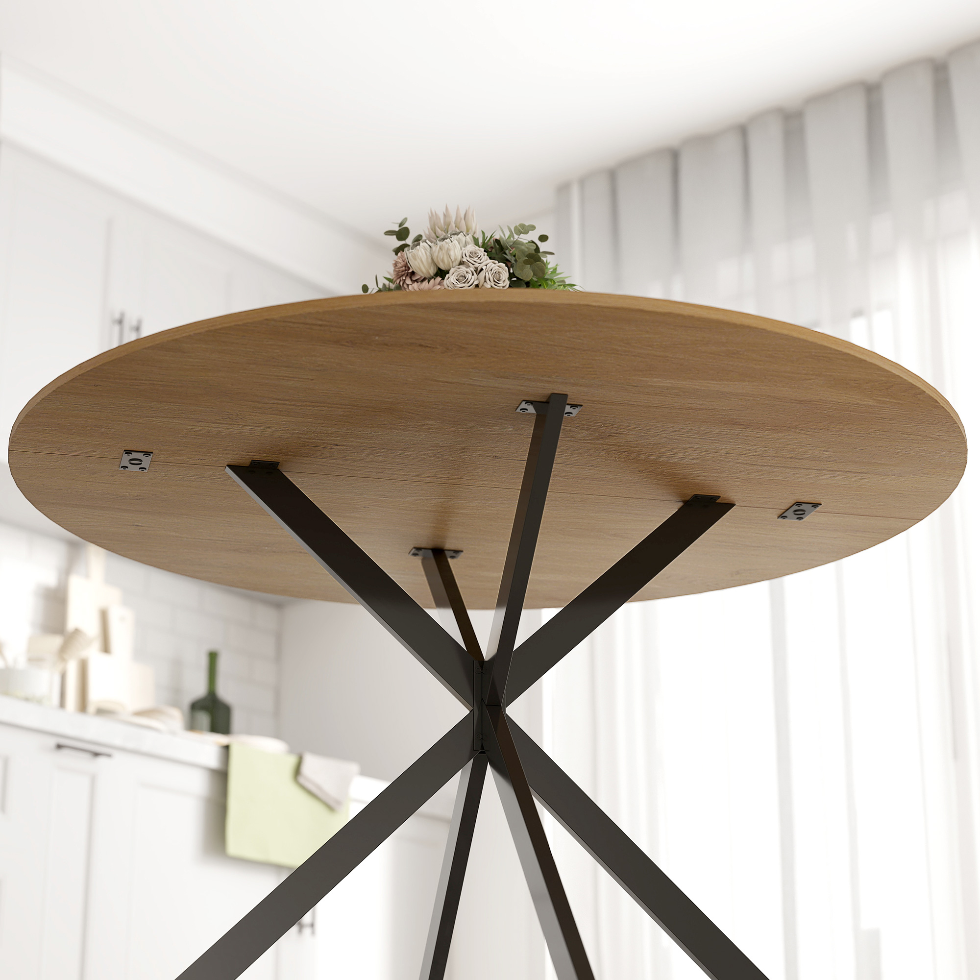 Piano del tavolo in legno con base in metallo nero, sormontato da un bouquet. Cucina sullo sfondo.