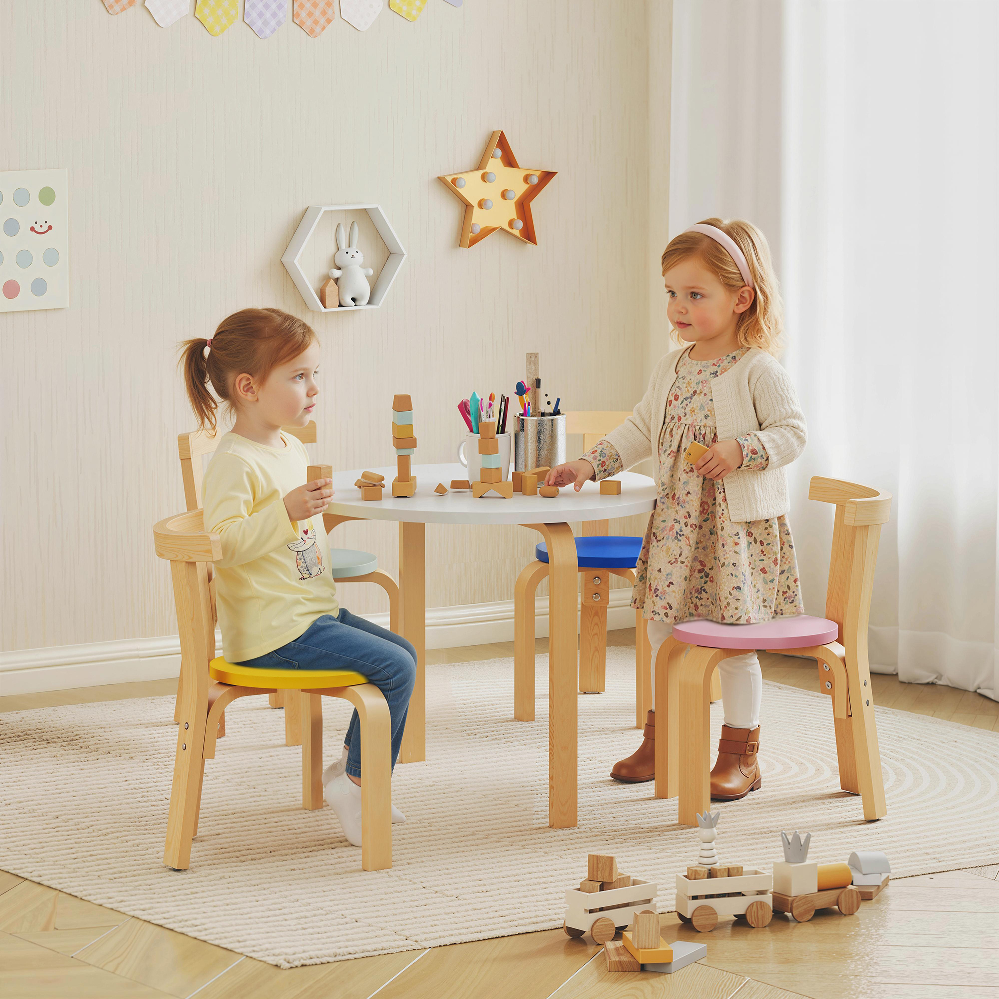 Due bambine a un tavolo con blocchi. Una bambina in giallo, una in abito floreale.