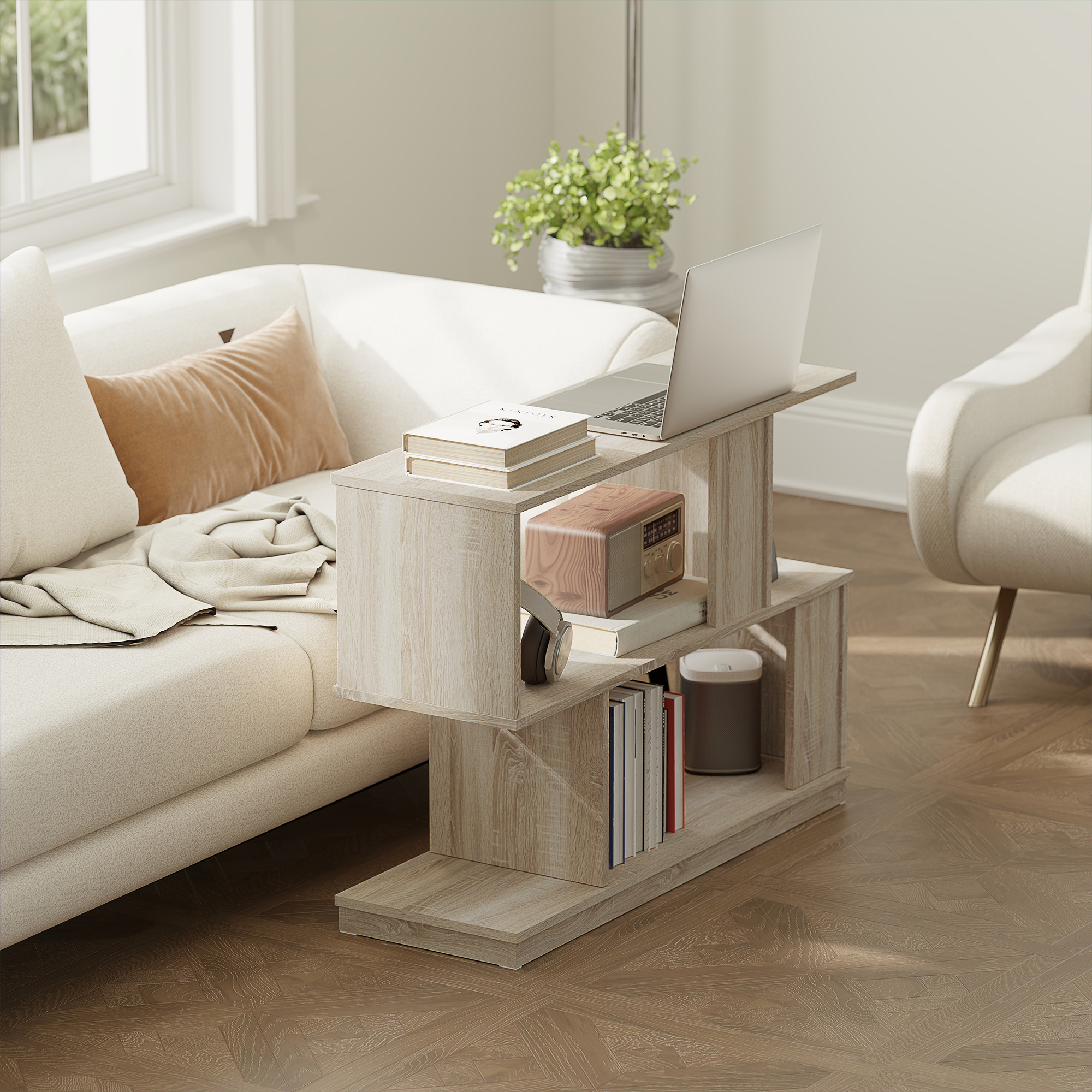 Un tavolino in legno chiaro con laptop, libri e radio accanto a un divano.