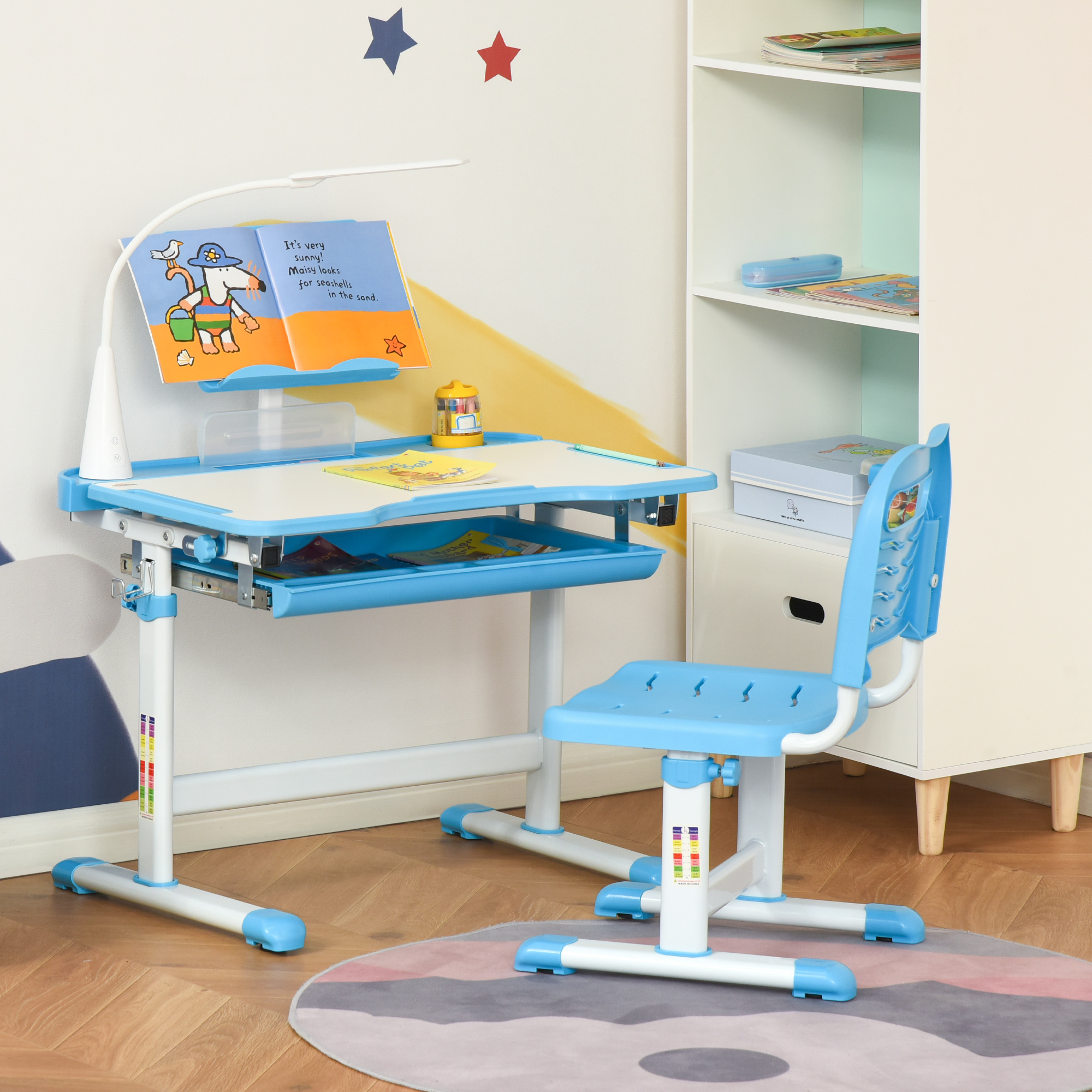 Scrivania e sedia regolabile per bambini blu e bianca con libro aperto, lampada e contenitore.