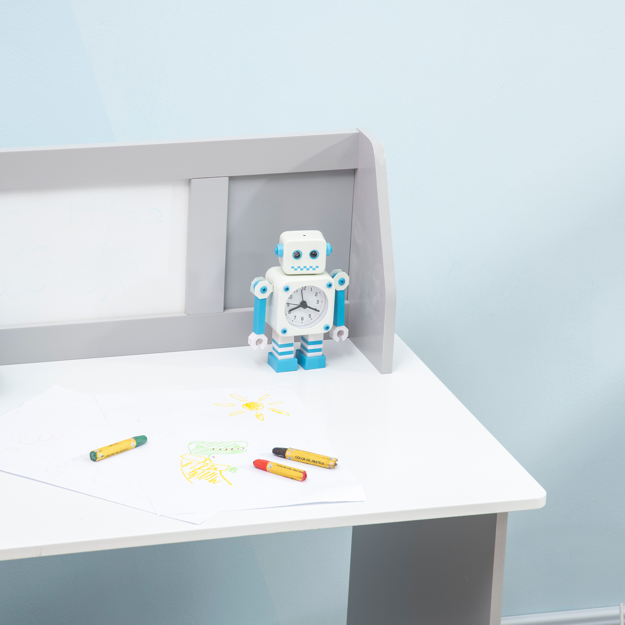 Una sveglia robot bianca è su una scrivania accanto a disegni e pastelli.