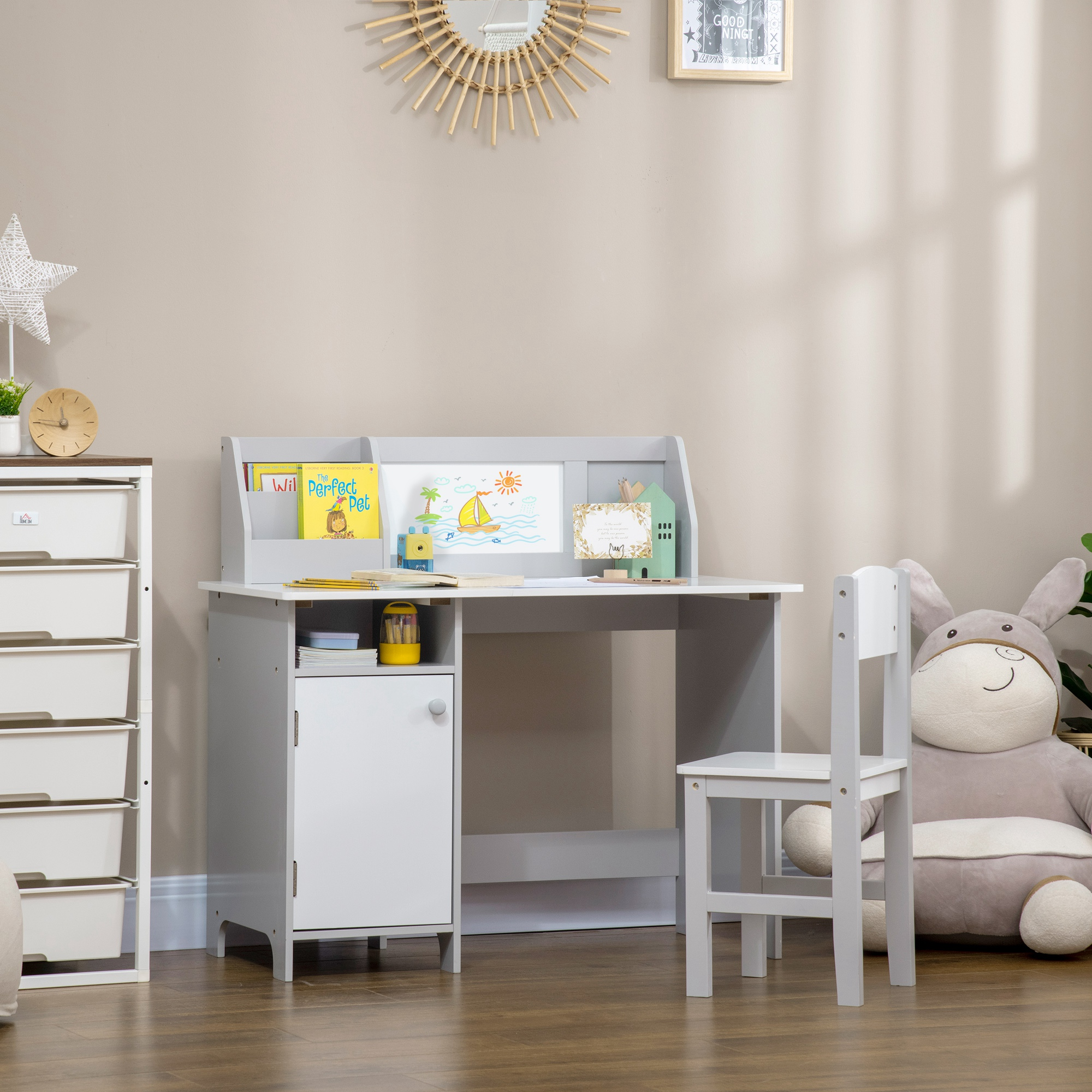 Una scrivania grigia per bambini con sedia, libri e un grande peluche.