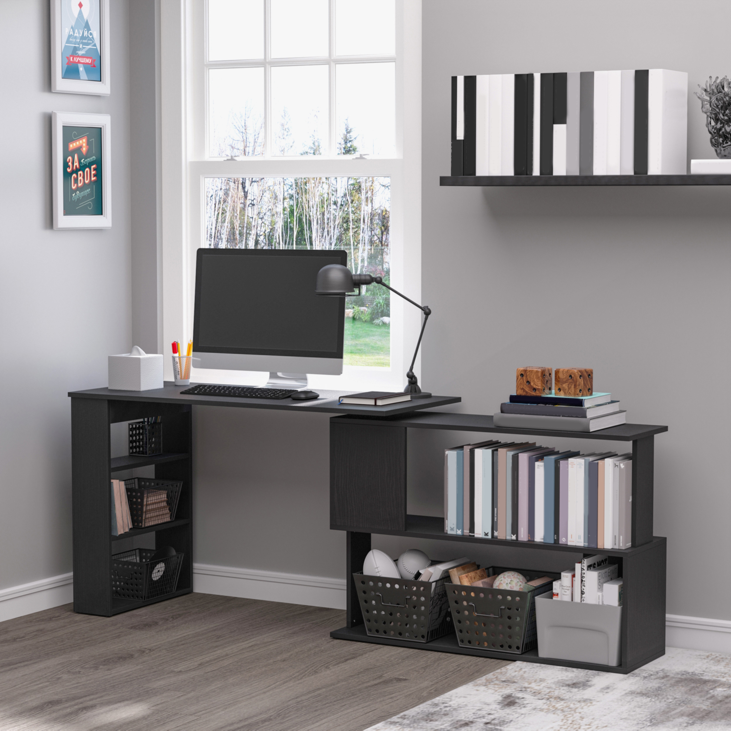 Una scrivania nera con computer, libri e decorazioni.