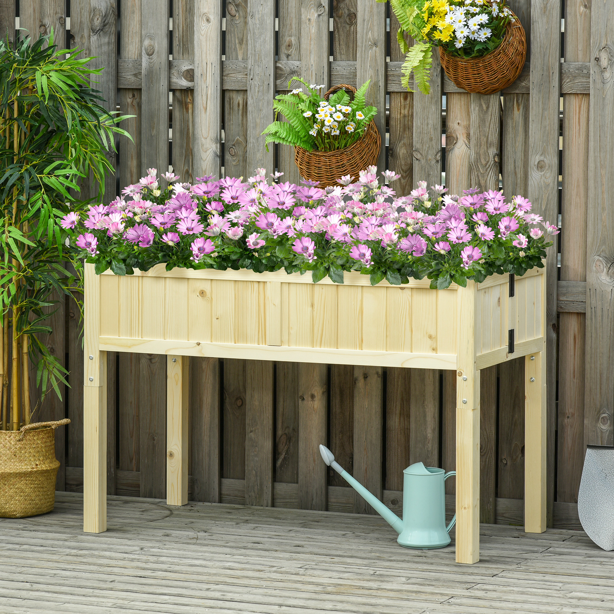 Un'aiuola rialzata in legno con fiori viola, bambù e un annaffiatoio.