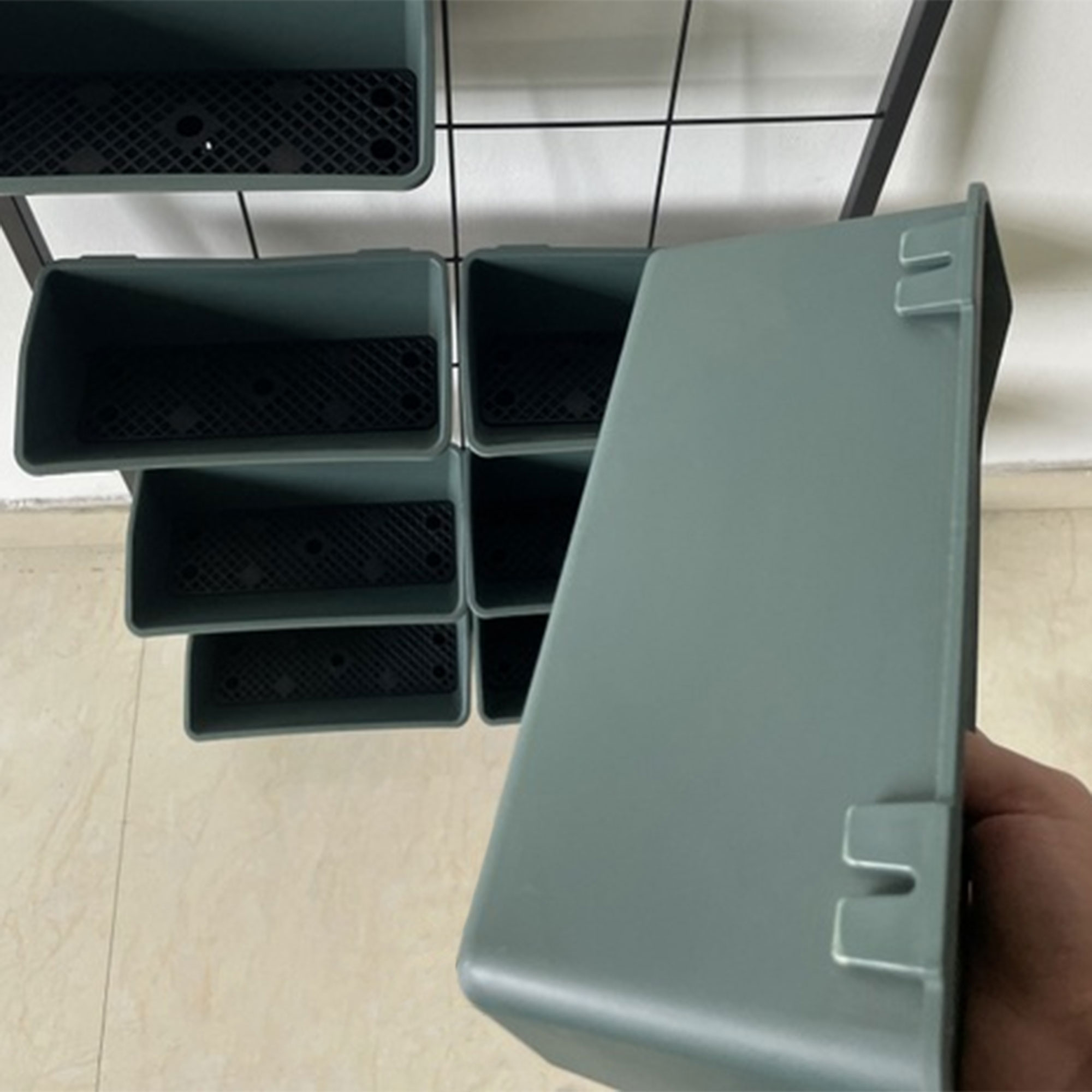 Fioriere grigie su uno scaffale, una fioriera tenuta da una mano.