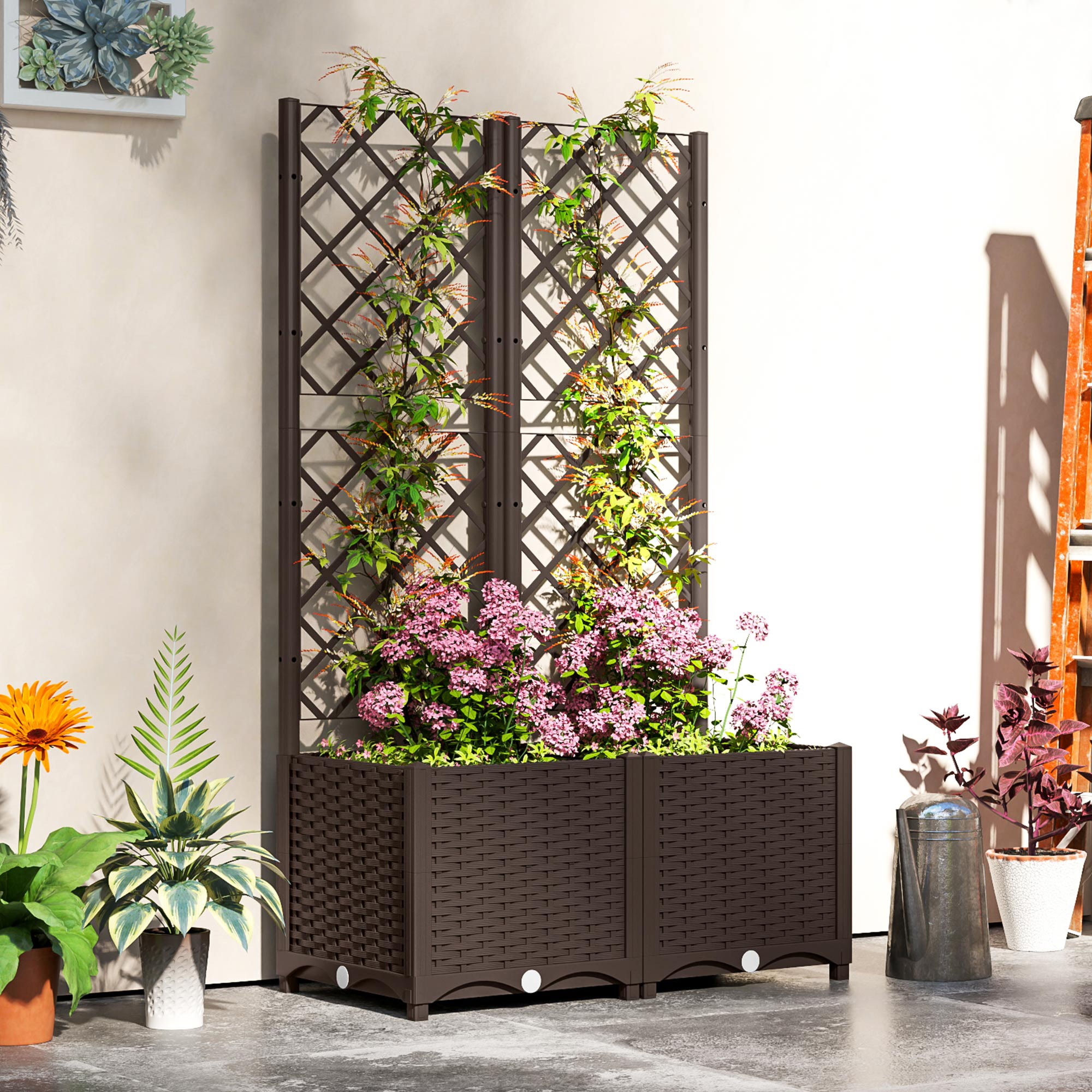Una fioriera marrone con fiori rosa e rampicanti verdi contro un muro beige.