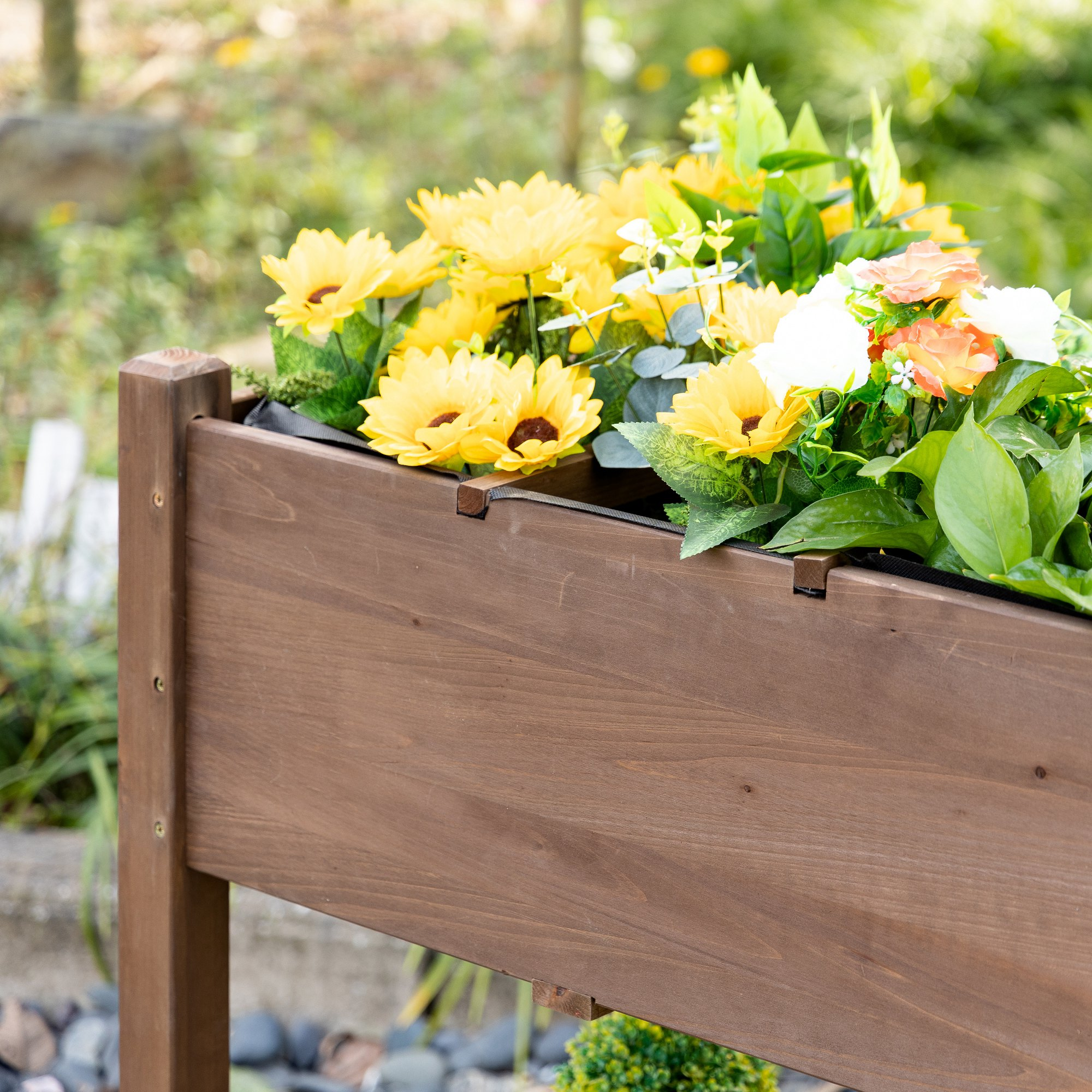 Una fioriera in legno piena di fiori artificiali gialli e arancioni.