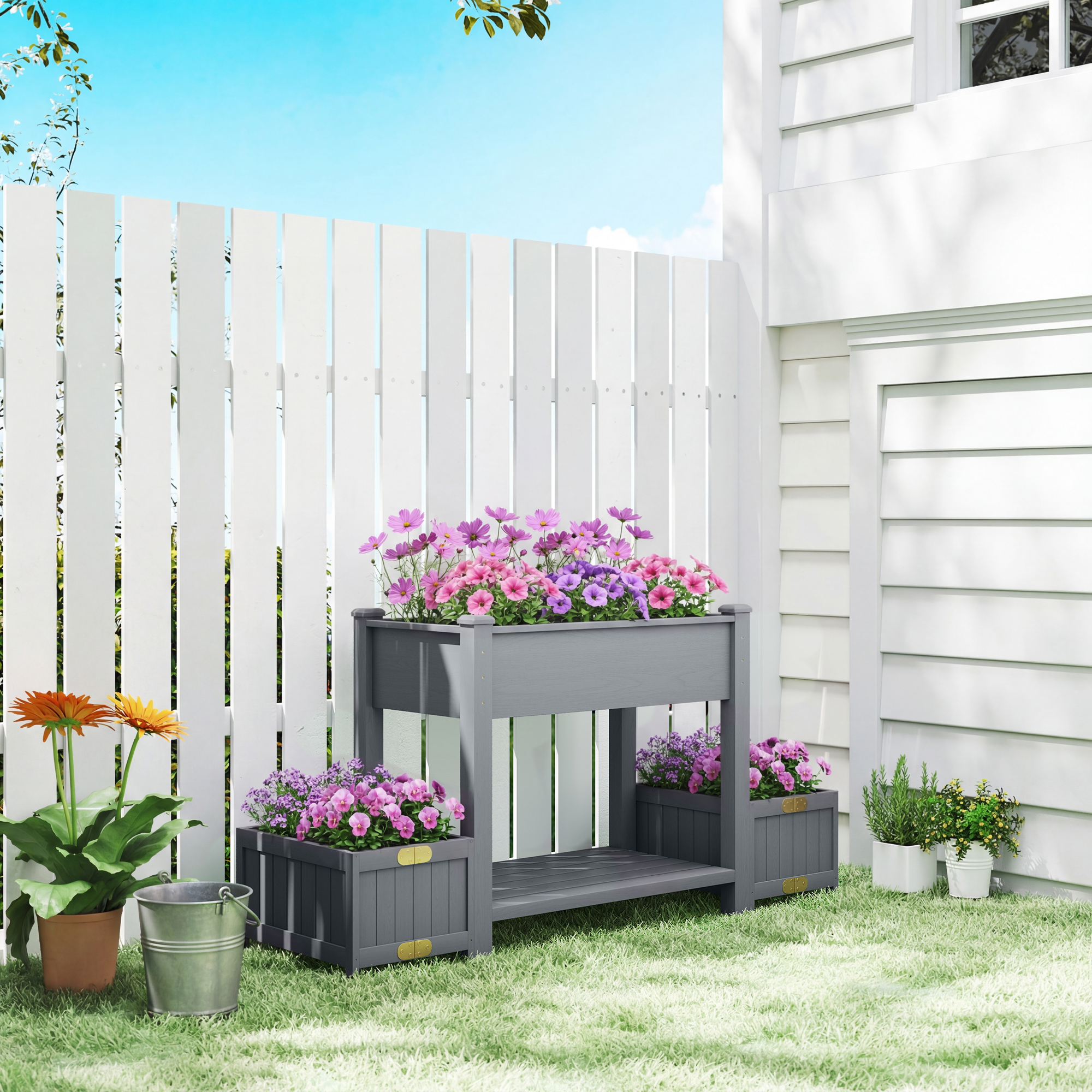 Una fioriera da giardino grigia con fiori colorati e una recinzione in legno bianca.